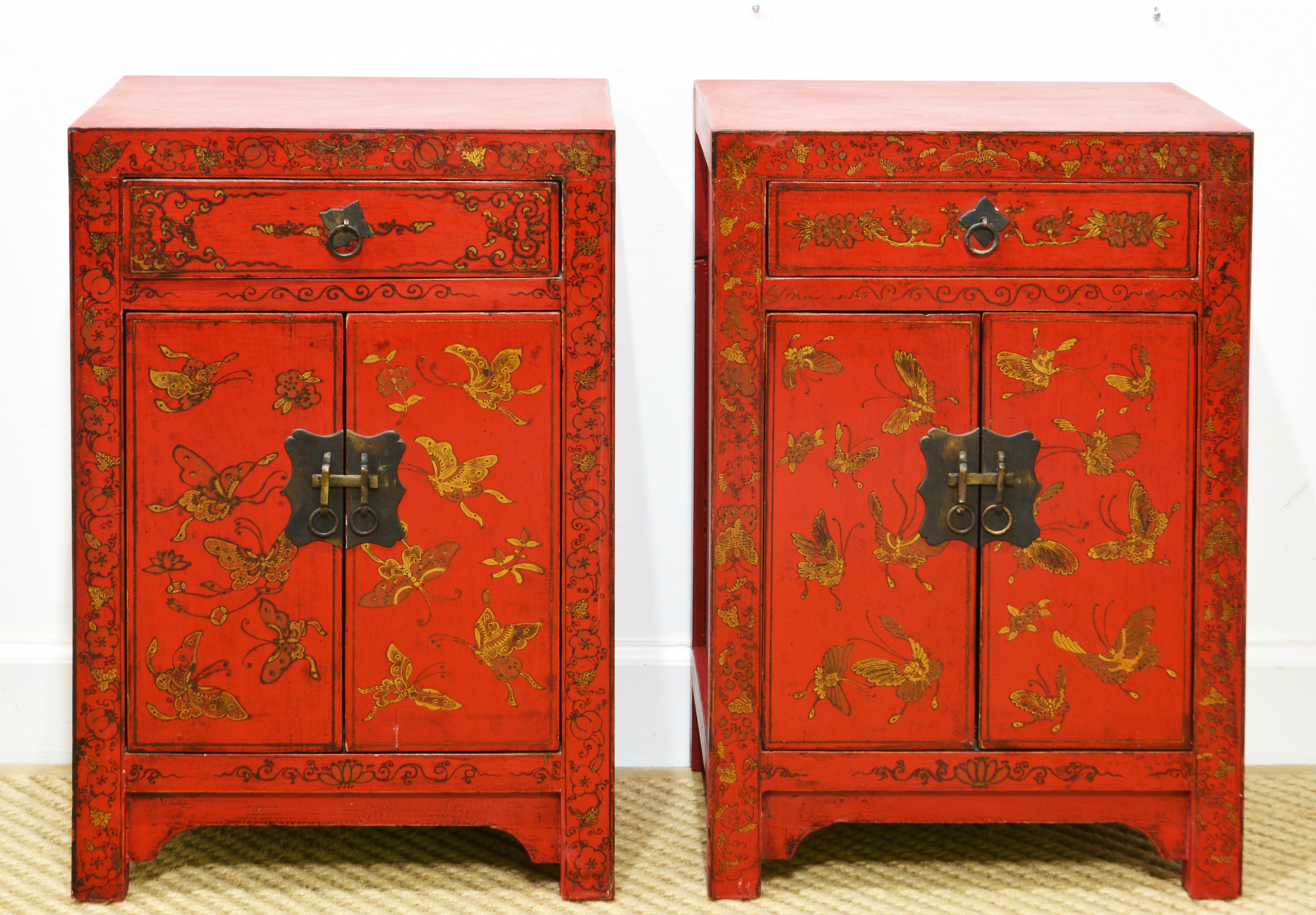 This adorable pair of Chinese red nightstands or end tables feature wonderfully gilt decorated fronts with many butterflies, foliage and stylized flowers. The drawers and doors are retaining their original dark patinated brass hardware. The