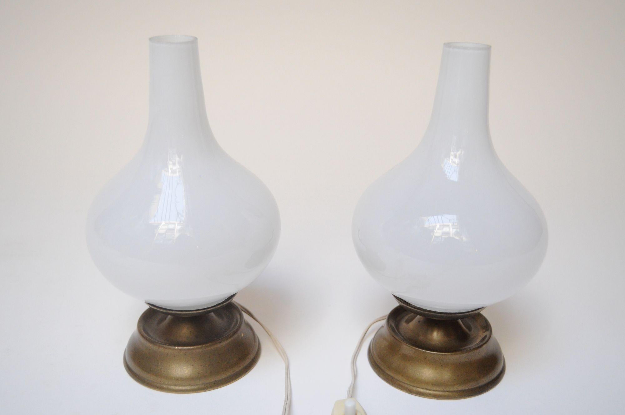 Pair of petite chamberstick/oil lamp-style bedside/table lamps (ca. 1950s, Italy).
Composed of sculptural opaline glass shades atop brass handled-bases.
Very good, vintage condition -- light wear/tarnish to the brass, and glass tops have somewhat