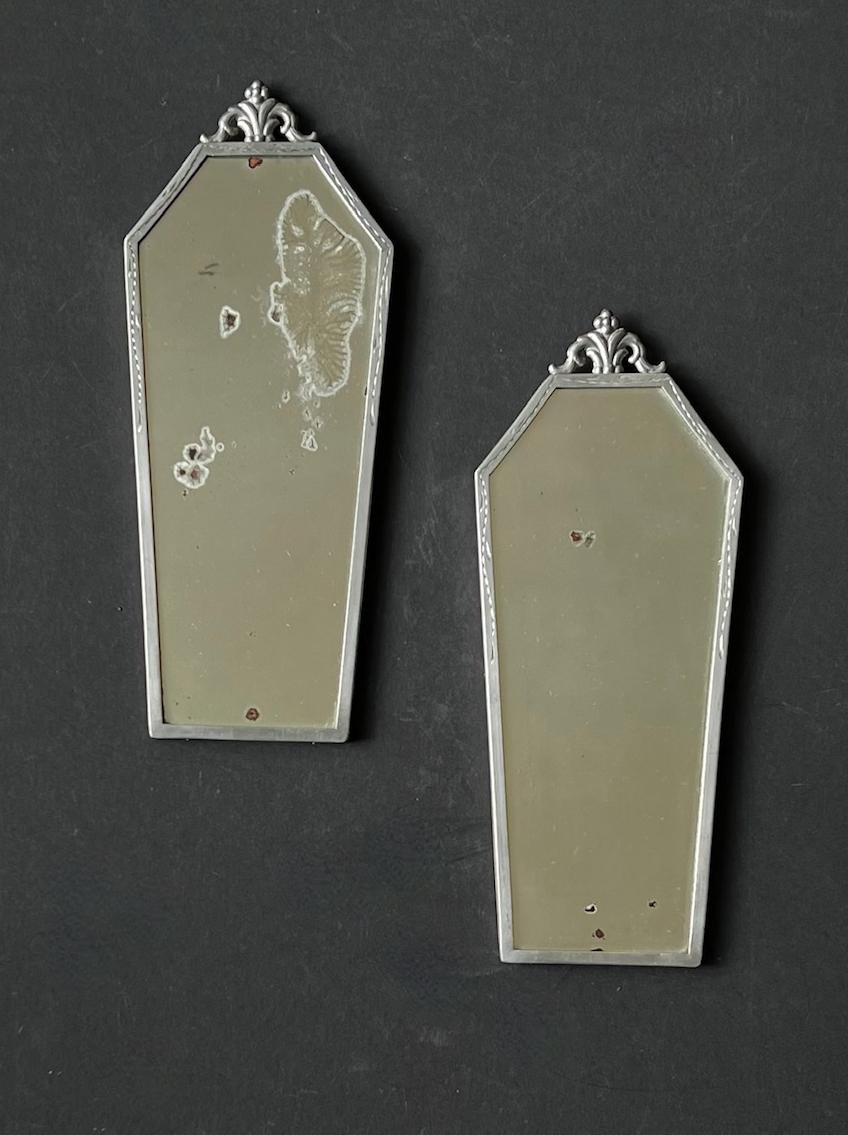 Ein Paar zierliche Wandspiegel - ehemalige Spiegelleuchten - aus Schweden, erste Hälfte des 20. Jahrhunderts, Art Deco Stil.

Attraktive dekorative Stücke mit gravierten Rahmen aus weißem (silberfarbenem) Metall, möglicherweise Zinn. Abgenutzte