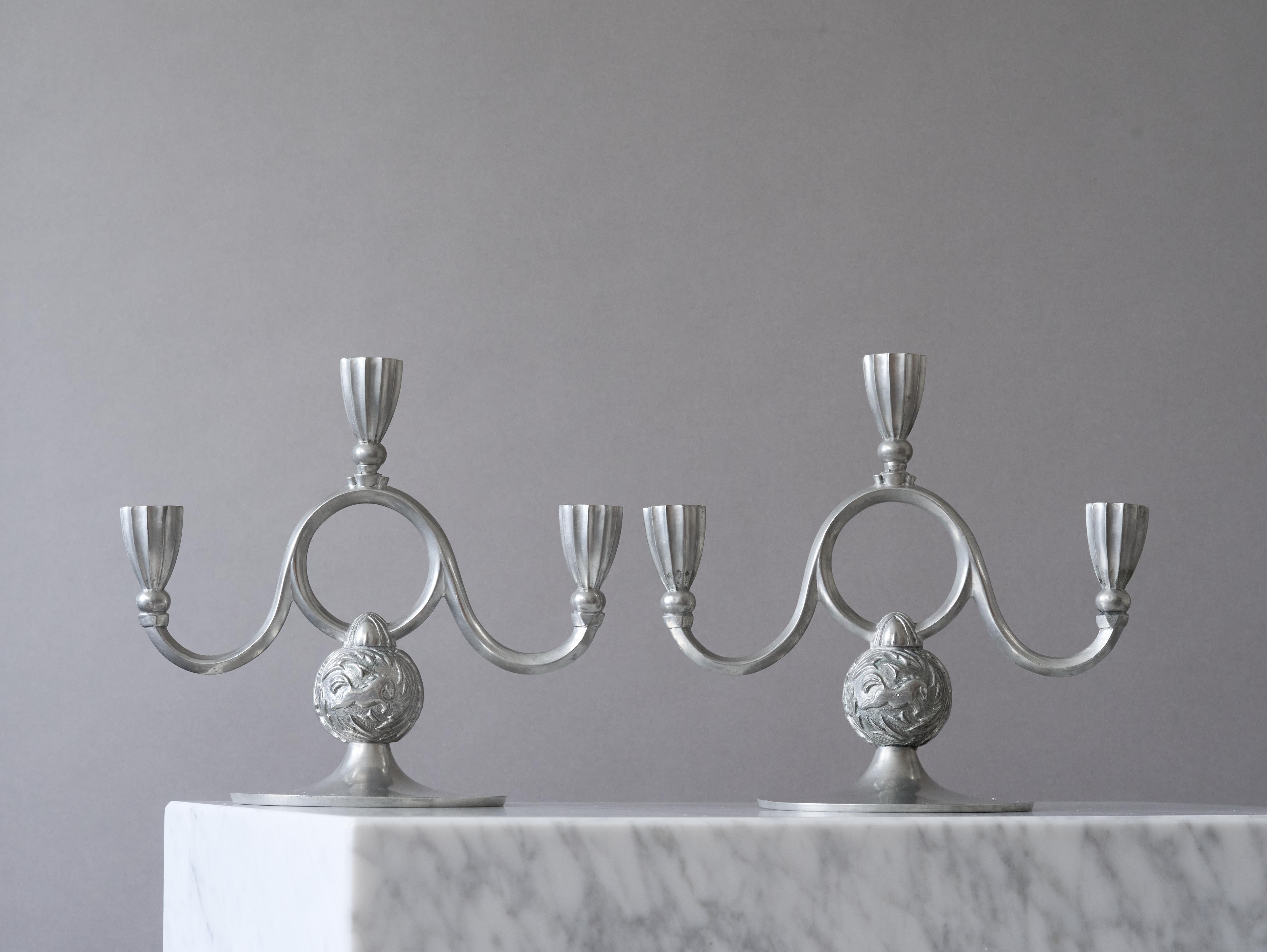 Una coppia di bellissimi candelieri in peltro Art Deco / Swedish Grace con un'incredibile patina. 
Realizzato da Harald Linder a Uddevalla, in Svezia, nel 1932. Attribuito a Edvin Ollers.

Ottime condizioni, con solo qualche leggero graffio.
Timbro