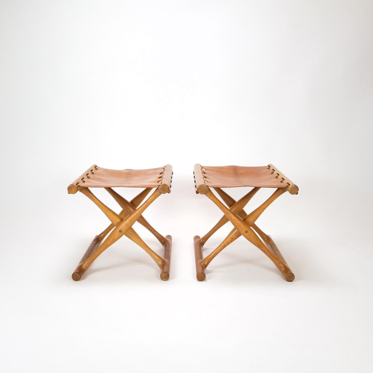 An original pair of Gudhøj folding PH43 Egyptian stools by Poul Hundevad for Vamdrup, Denmark, 1960s. Based on a bronze age folding stool found at Guldhøj in Denmark. Great patina to the leather and oak.