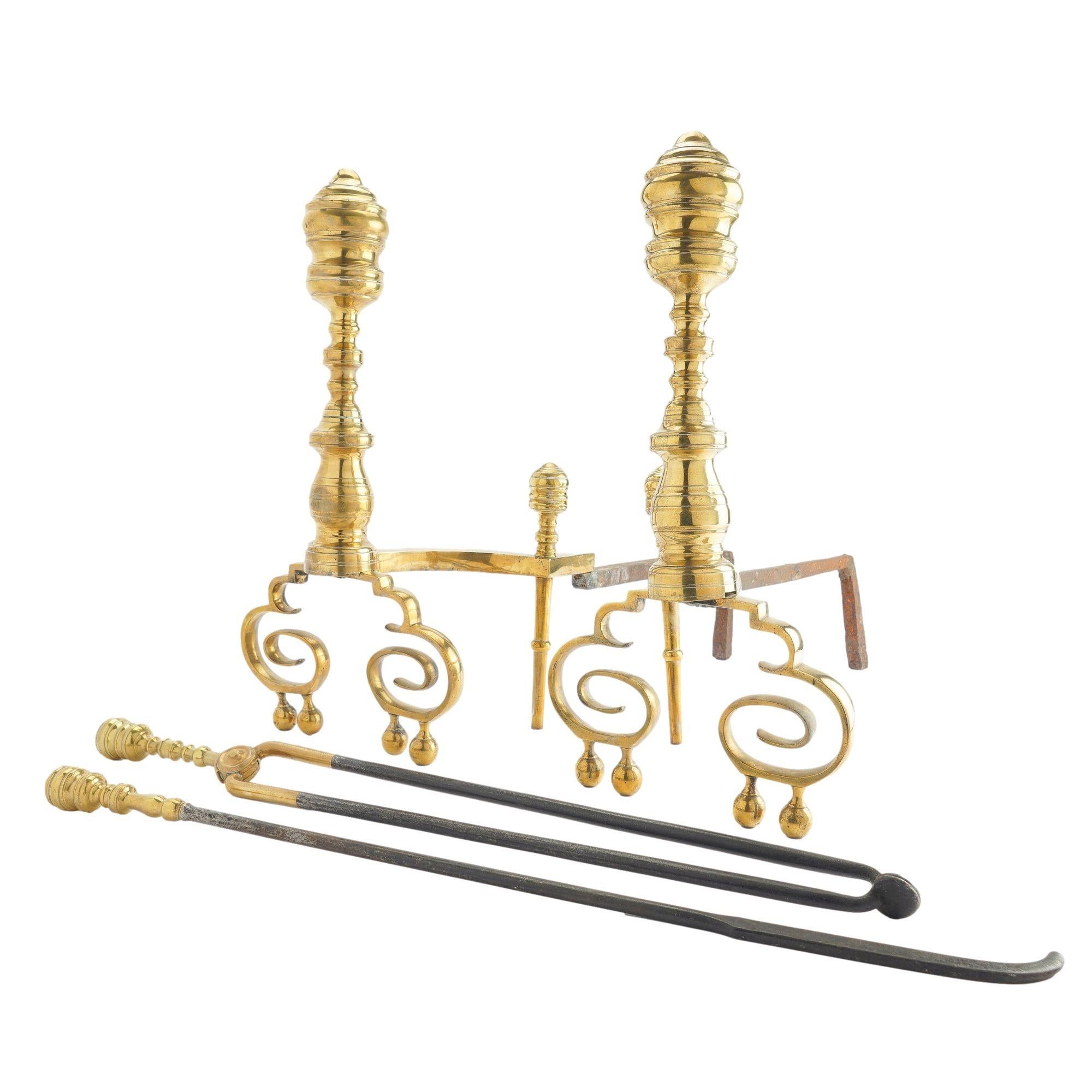 Pair of American cast brass baluster form Neoclassic andirons with matching fire tools. The andirons feature scrolled legs on double pairs of ball feet, and the gated log rests are fitted with cast brass baluster finial log stops. The baluster