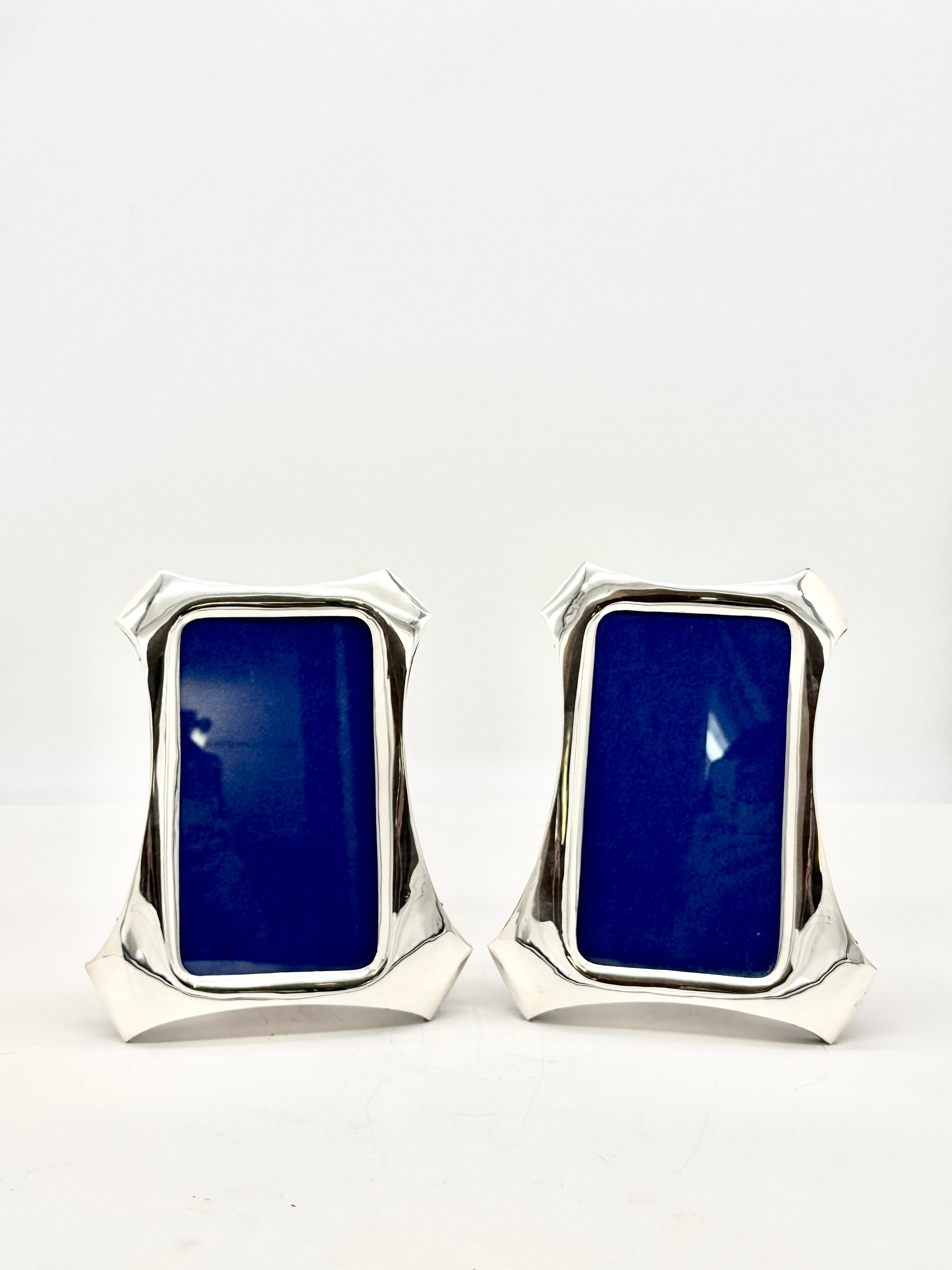 Pair of antique English sterling silver photograph frames of curved and shaped form with bold geometric borders, made by Sanders & Mackenzie and hallmarked in 1912, one in Birmingham and the other in Chester.
