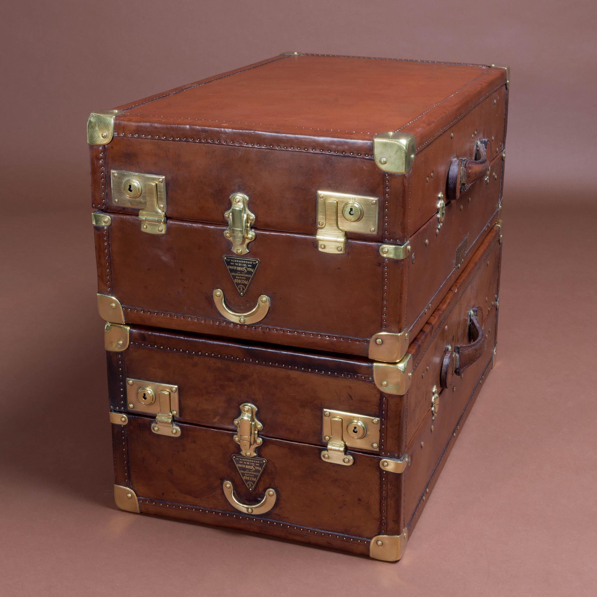 Austrian leather covered wardrobe trunks, by Vienna based luggage company Paul Stark, circa 1920. Fitted internally with hangers and rail. Heavy leather handles, brass rivets, locks, catches and corners as well as re-enforced edging. The brown