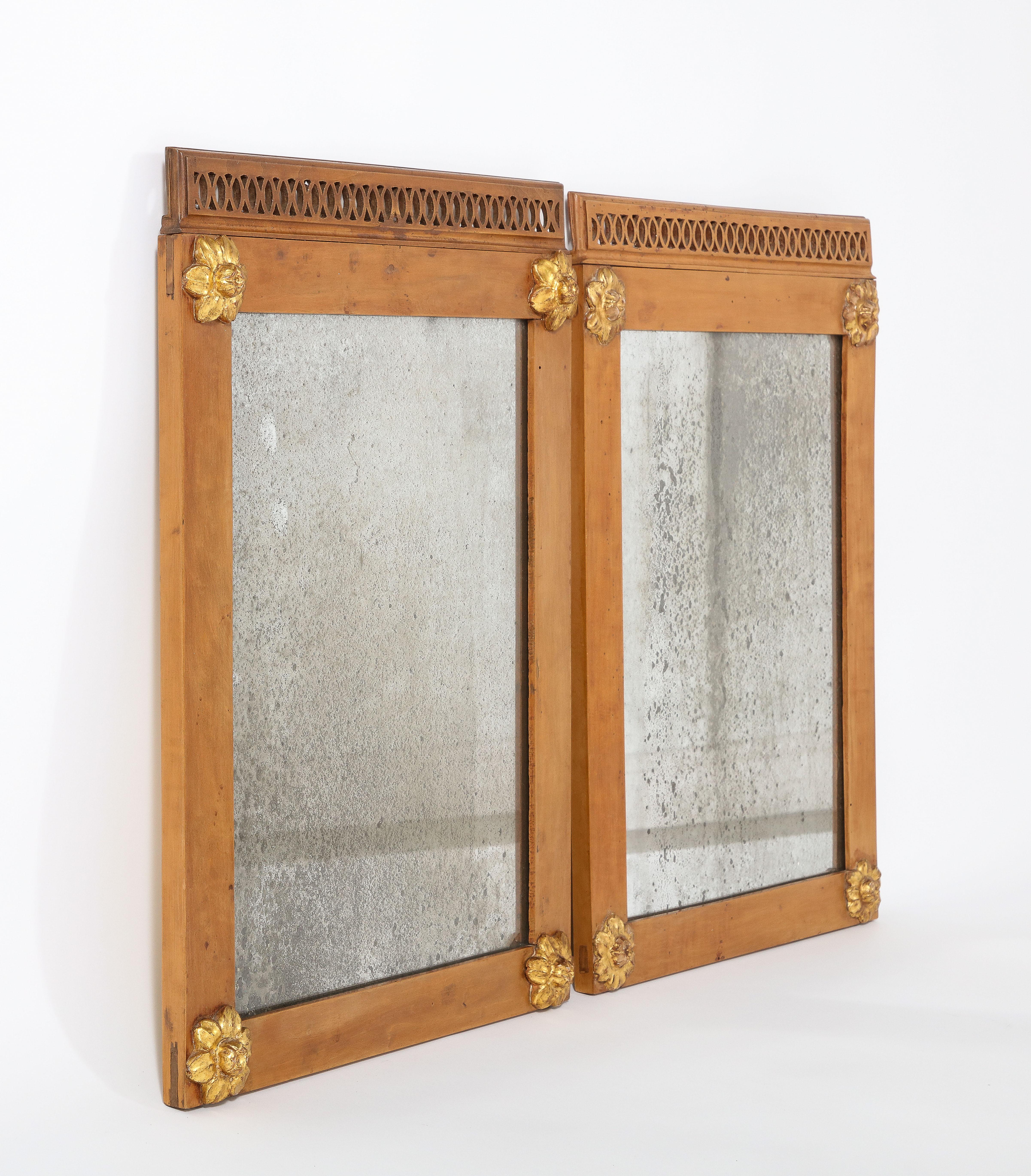 Early and rare pair of Piedmontese walnut framed mirrors with delicate carved and gilded rosettes decorating each corner, the top with cut out pierced gallery carving, with its original mercury glass. A beautiful example of Italian Neoclassical