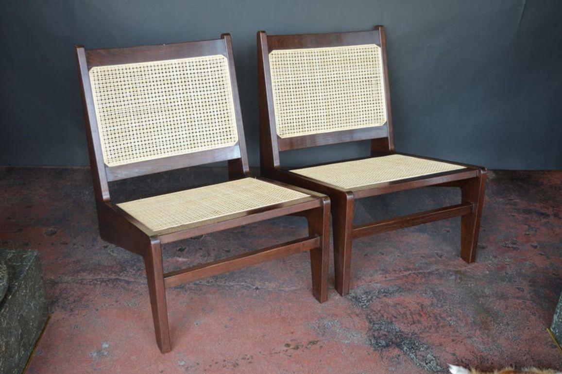 A striking pair of mid-century cane lounge chairs in the style of Pierre Jeanneret's iconic 'Kangourou' model PJ-SI-59-A, originally designed for Chandigarh, India in the 1950s. These chairs embody the distinctive V-leg silhouette and minimalistic