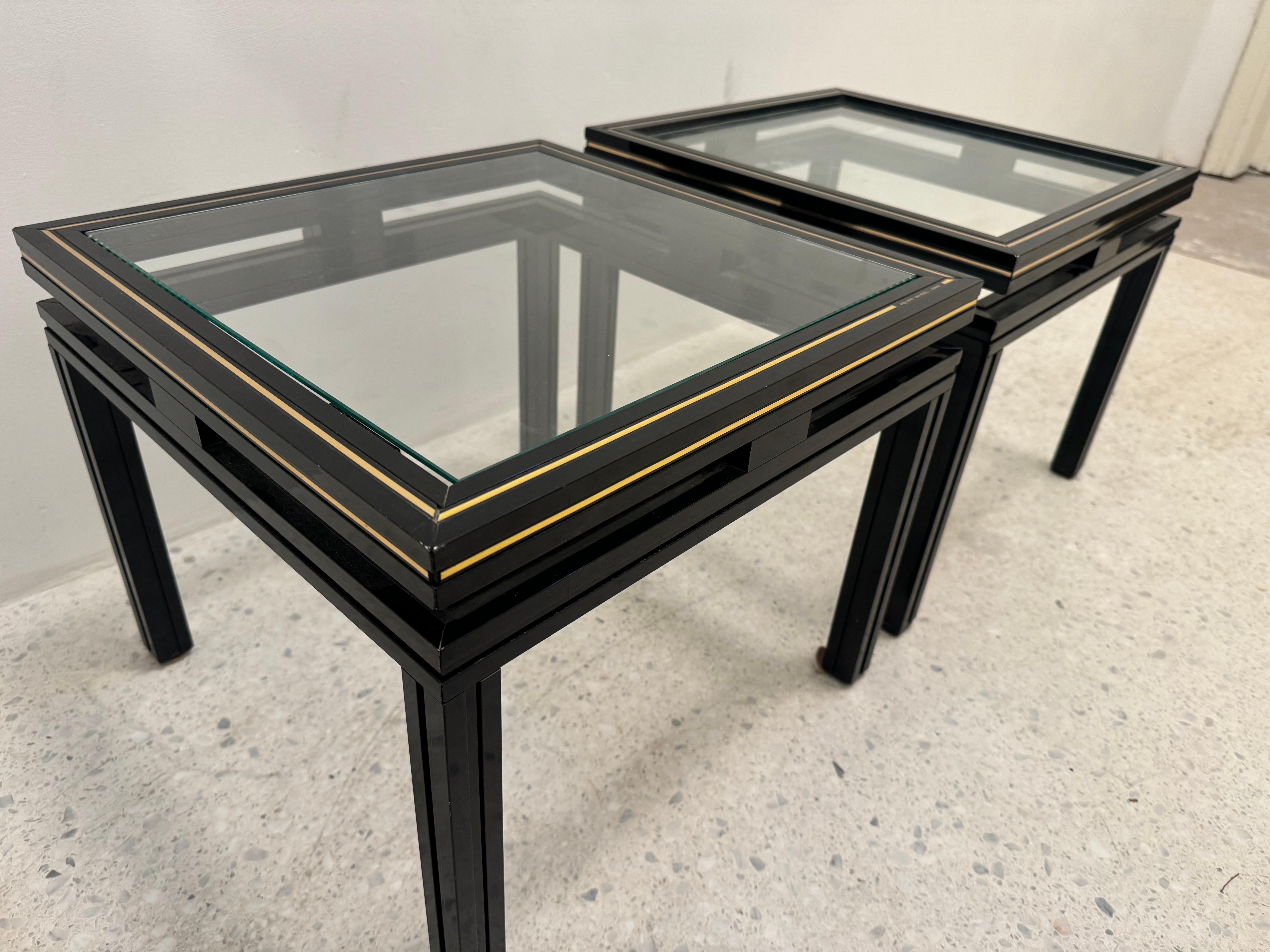 Elegant pair of vintage side tables by renowned French designer Pierre Vandel, circa 1970s. Featuring sleek black lacquered aluminum frames with signature brass trim and inset glass tops, these tables embody the chic, modernist aesthetic of