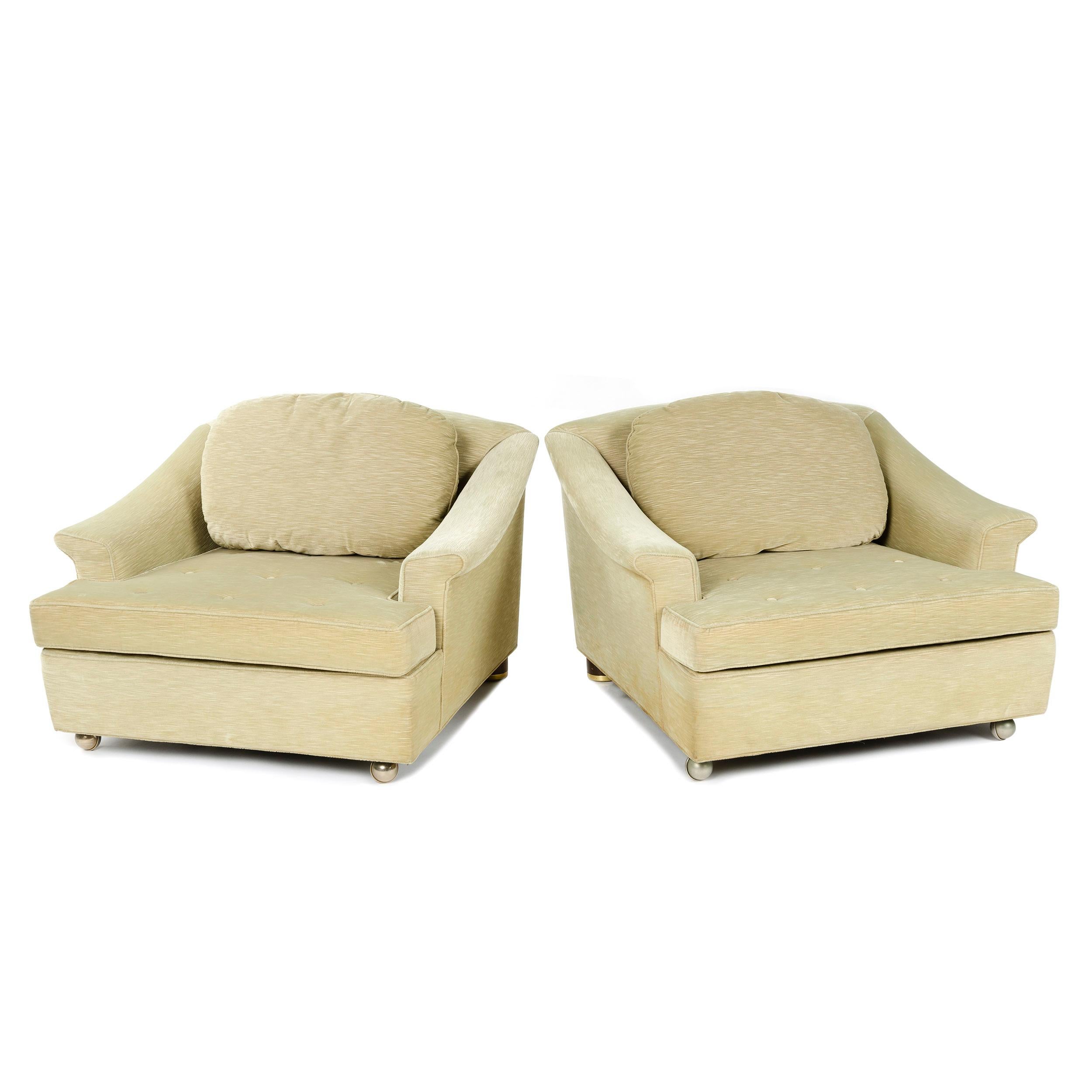 A pair of generously proportioned pillow back chairs with front casters and original upholstery.