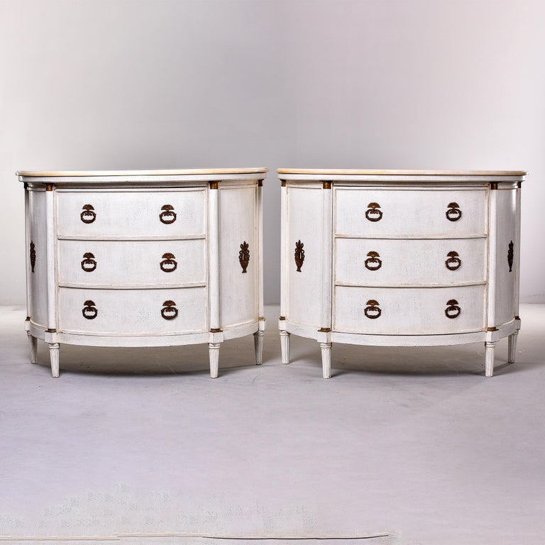 Found in England, this pair of circa 1940s pine demi lune cabinets have cream colored marble tops. These cabinets are a true pair with false drawer fronts that are hinged cabinet doors that swing open from opposite sides. Reeded legs and original
