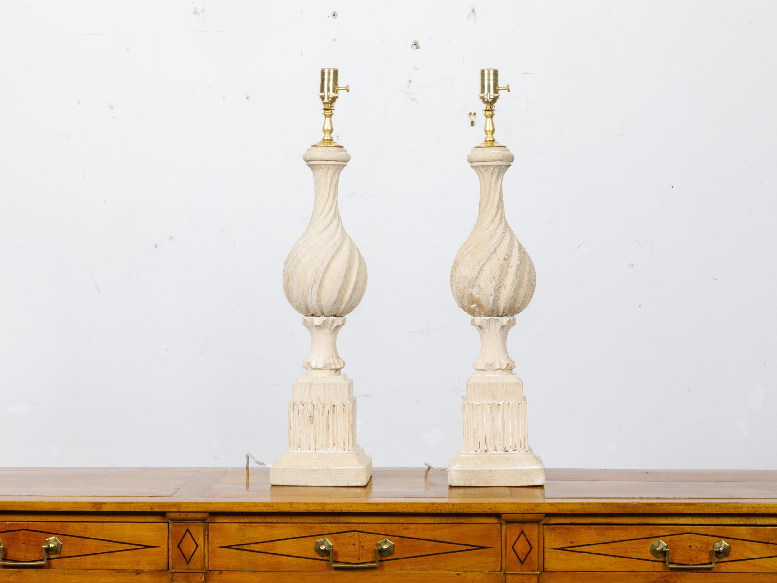 A pair of natural pine finials from the 19th century with twisted motifs and traces of white paint, made into table lamps wired for the USA. This pair of table lamps, ingeniously crafted from 19th-century natural pine finials, combines historical