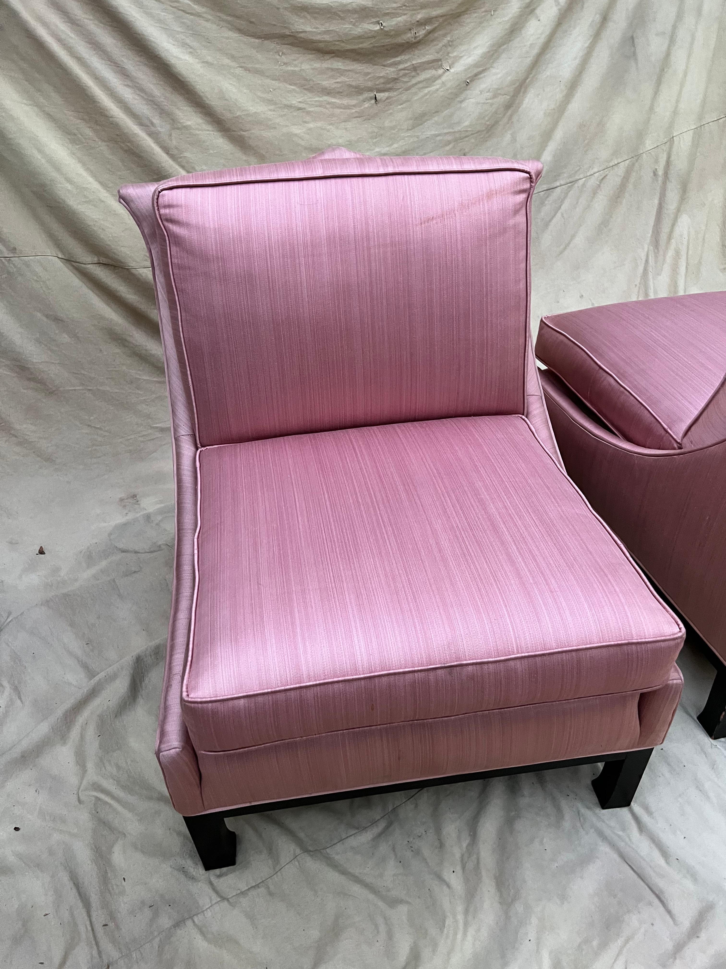 Pair of hollywood regency slipper chairs. The chairs have been upholstered in a striated pink with some sheen to it. A complement to any sitting room or bedroom.