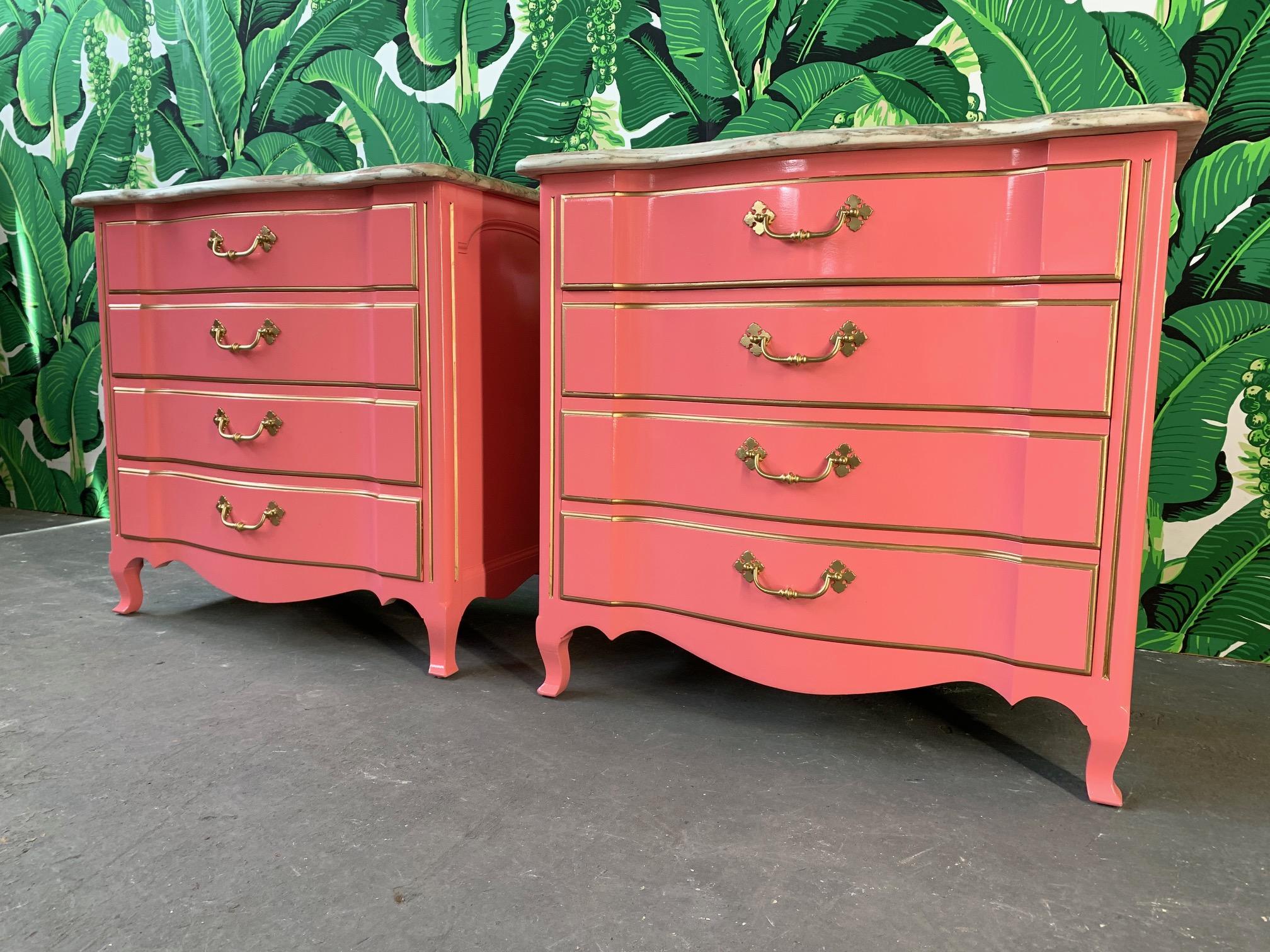 Newly restored pair of commodes by Wm. A. Berkey Furniture / John Widdicomb finished in high gloss pink lacquer. Marble tops and brass hardware, along with gold gilt detailing. Excellent condition with no cracks or chips to marble and only minor