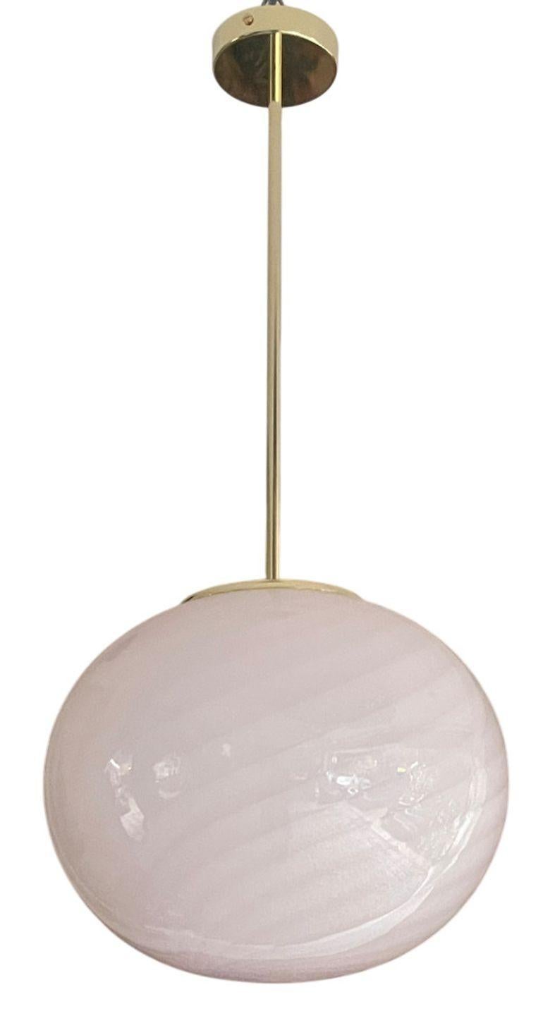 Elegante coppia di bellissimi lampadari a globo in vetro di Murano degli anni '70. Ogni pezzo è caratterizzato da un vetro soffiato a mano di colore rosa tenue con un disegno a volute che aggiunge movimento e una sottile consistenza.
I globi sono