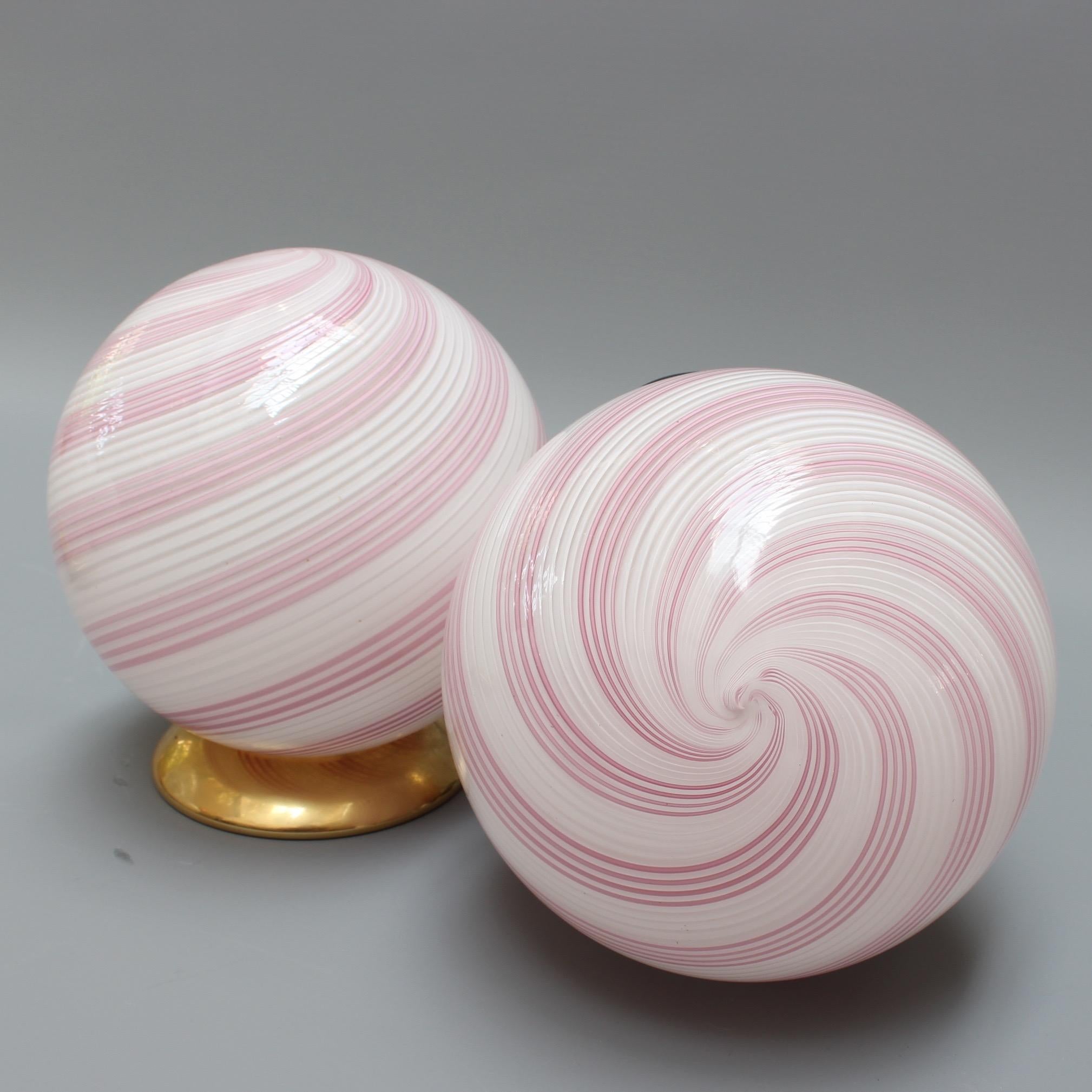 Pair of pink swirl Murano glass globe table lamps, circa 1960s. Elegant and stylish, these blown Murano glass globe lamps provide a source of lighting which is both functional and decorative. The pink swirls beautifully complement the brass-colored