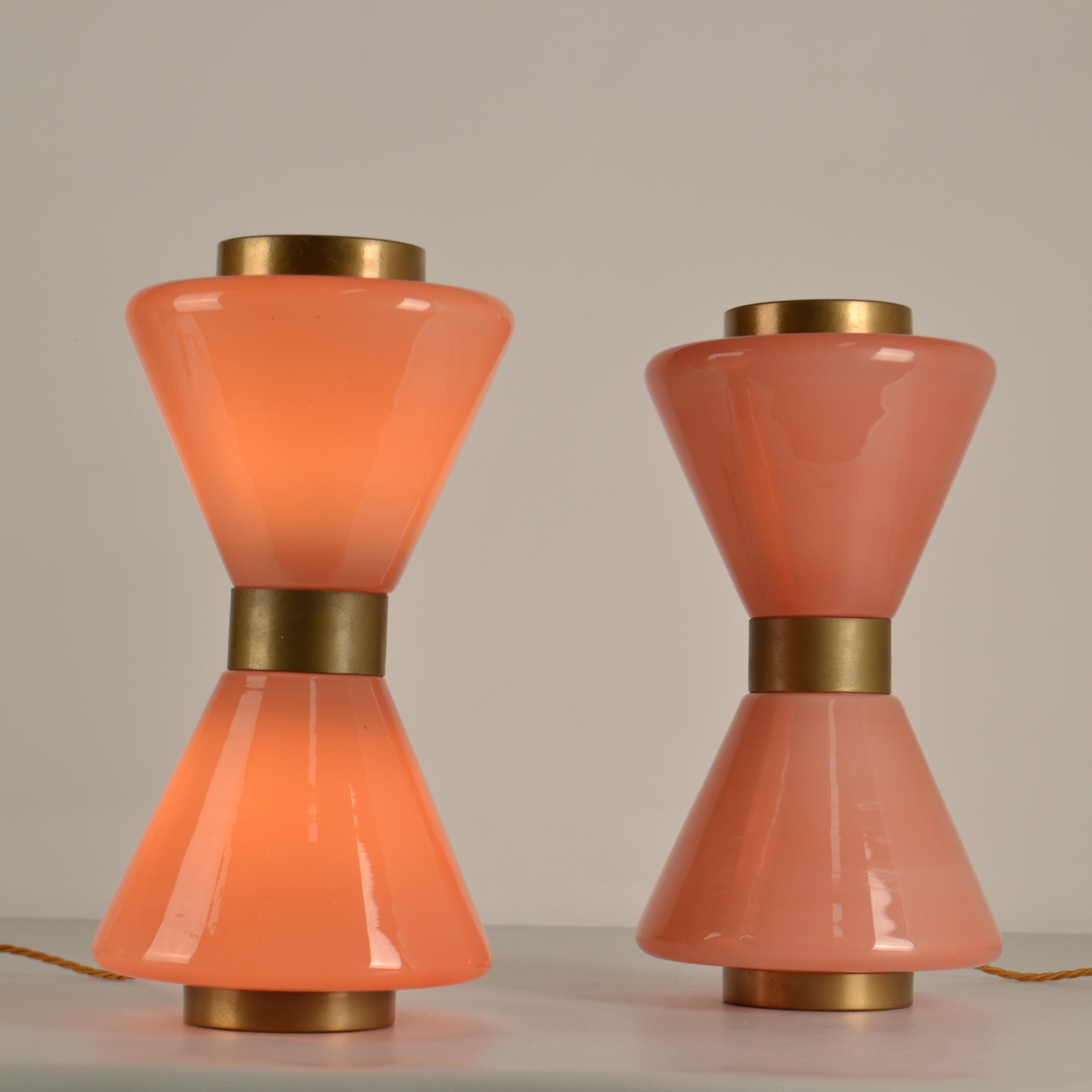 Pareja de lámparas de sobremesa rosas de Murano de los años 50 en forma de reloj de arena al estilo de Vistosi que dan una luz muy atmosférica. El cristal está revestido en la parte superior, central e inferior con metal de color latón. El cristal