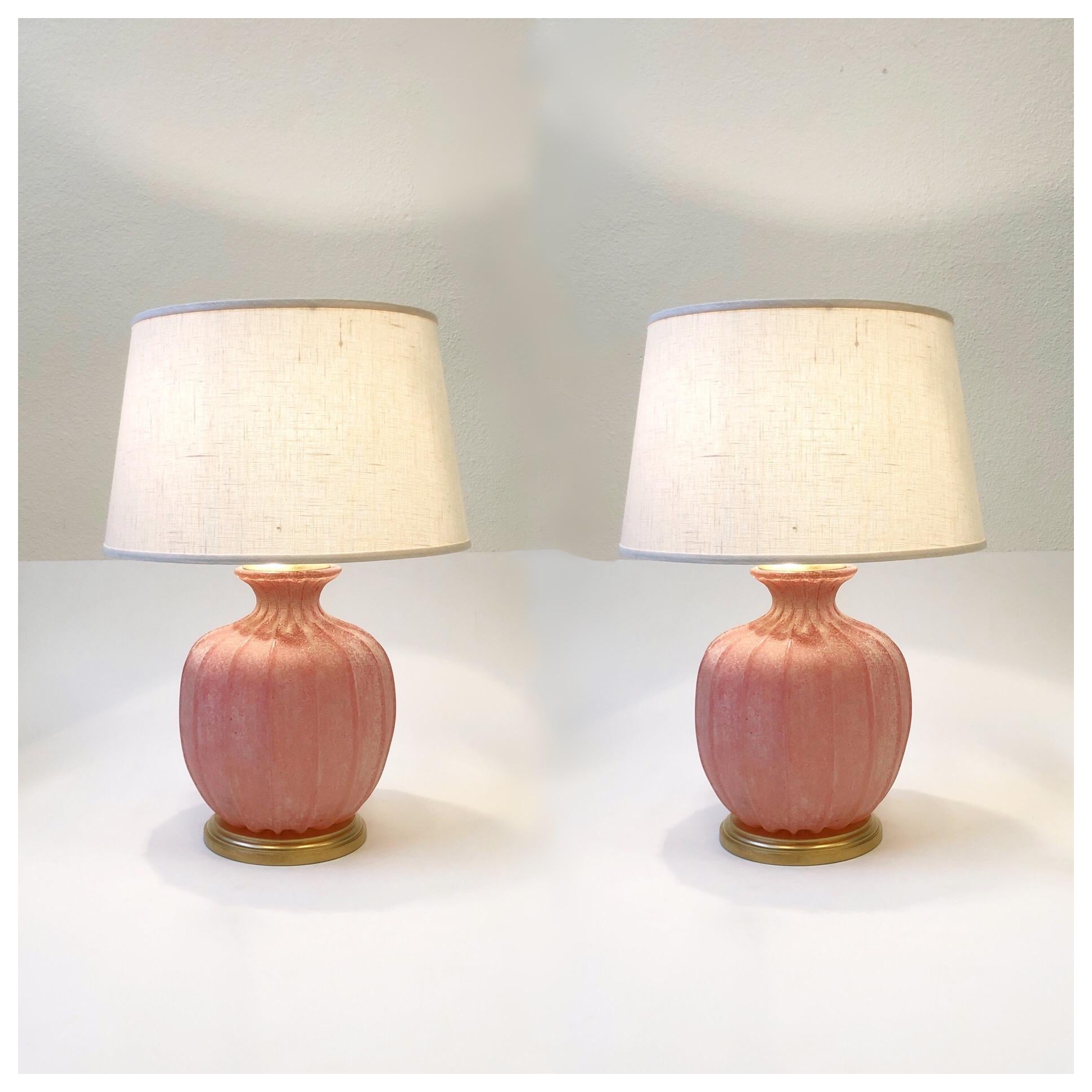 A pair of 1970s Italian pink Scavo Murano glass and satin brass table lamps by Seguso Vetri d’Arte. The lamps have been newly rewired and have new vanilla linen shades. The hardware is satin brass and the base is gilded wood. Both lamps are signed