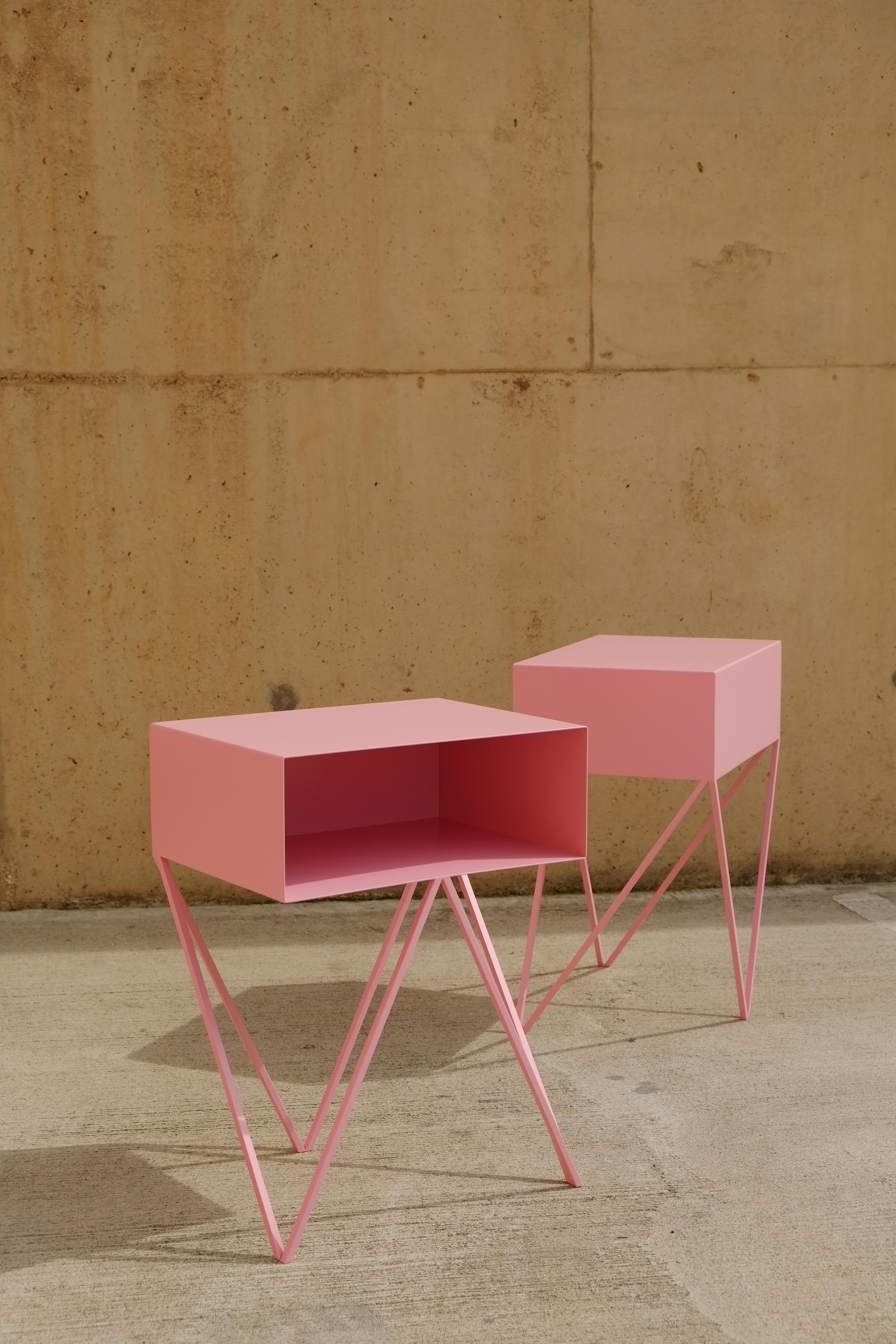 A pair of pink Robot bedside tables. The Robot side table features an open shelf on zig zag legs. A fun and functional design made of solid steel, powder-coated in pink. The clean lines look great against period details as well as in modern spaces.