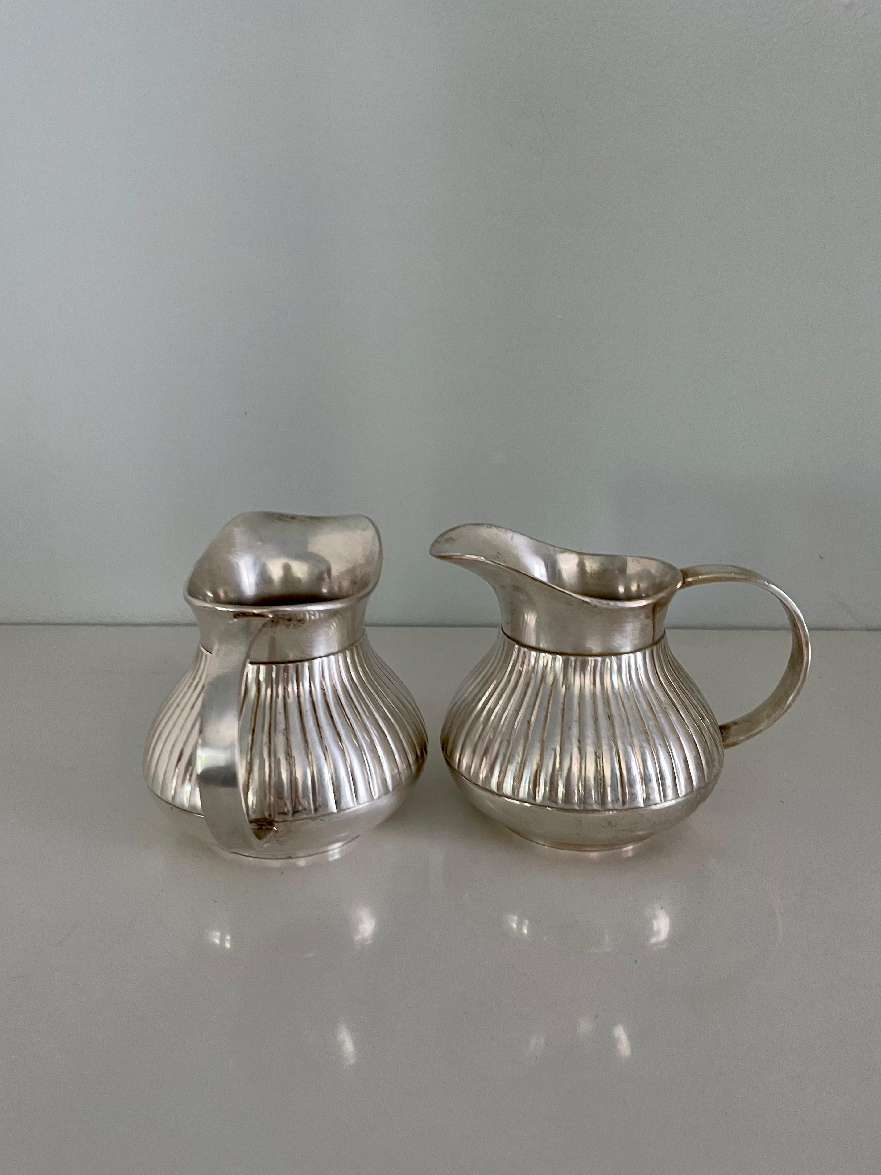 Patinated Pair of Pinstriped Silver Pitchers For Sale