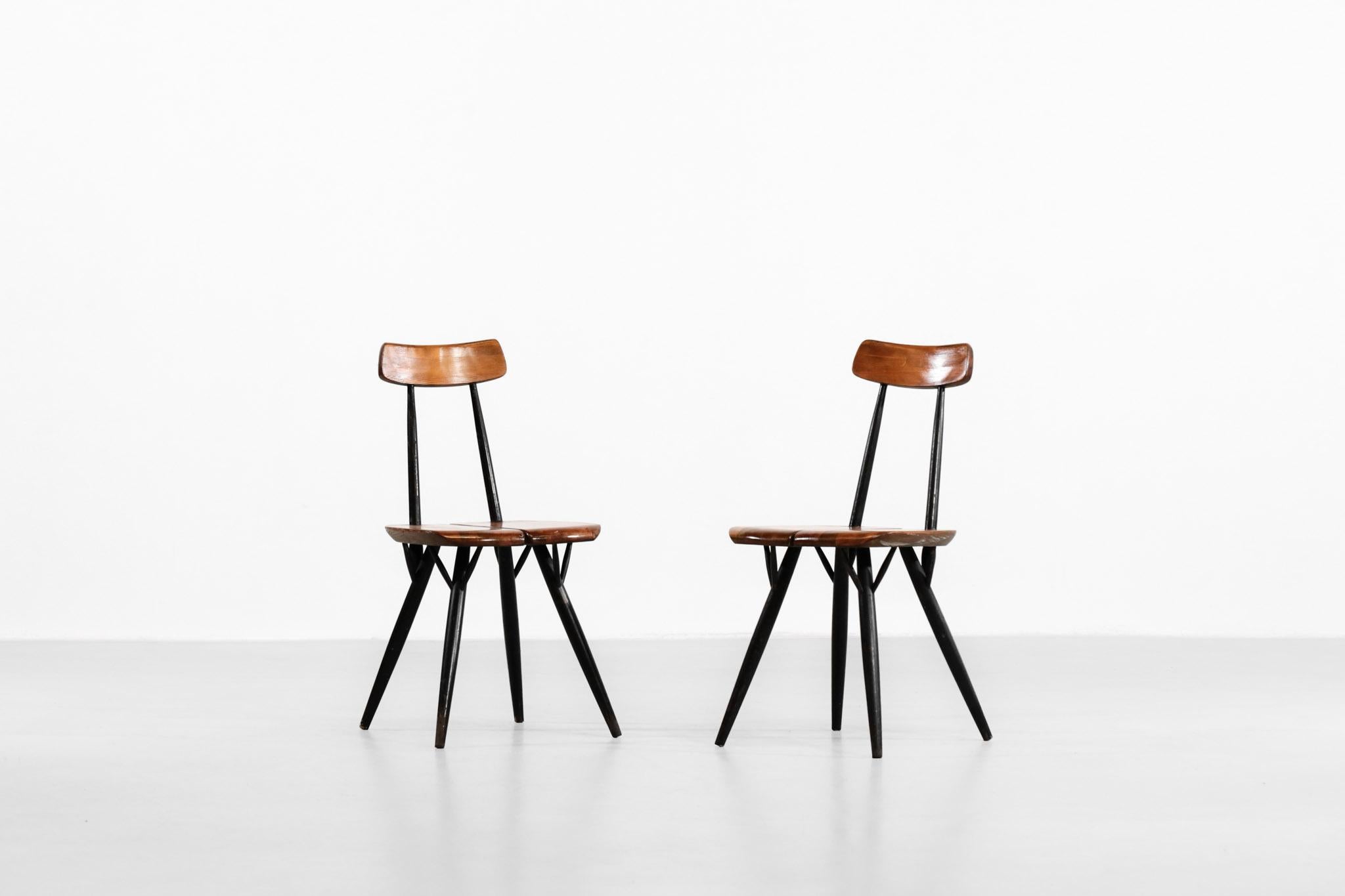 Pair of Pirkka chairs designed by Swedish designer Ilmari Tapiovaara. Made of beechwood painted in black with a seat in pine. Wear consistent with age and use.