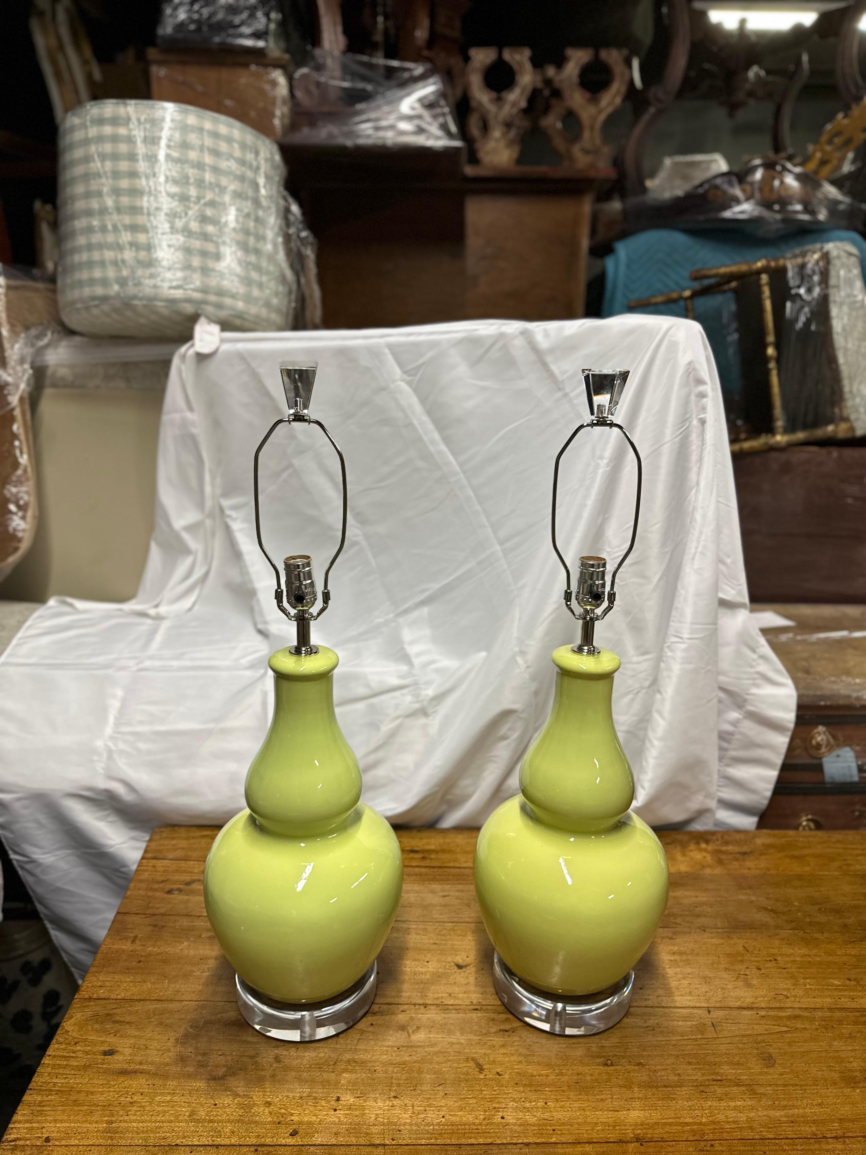 The maker of these lamps are unknown.
This pair of pistachio green ceramic lamps with shades and lucite bases exudes elegance and modern sophistication. The soft, muted hue of pistachio green adds a subtle pop of color to any space, while the glossy