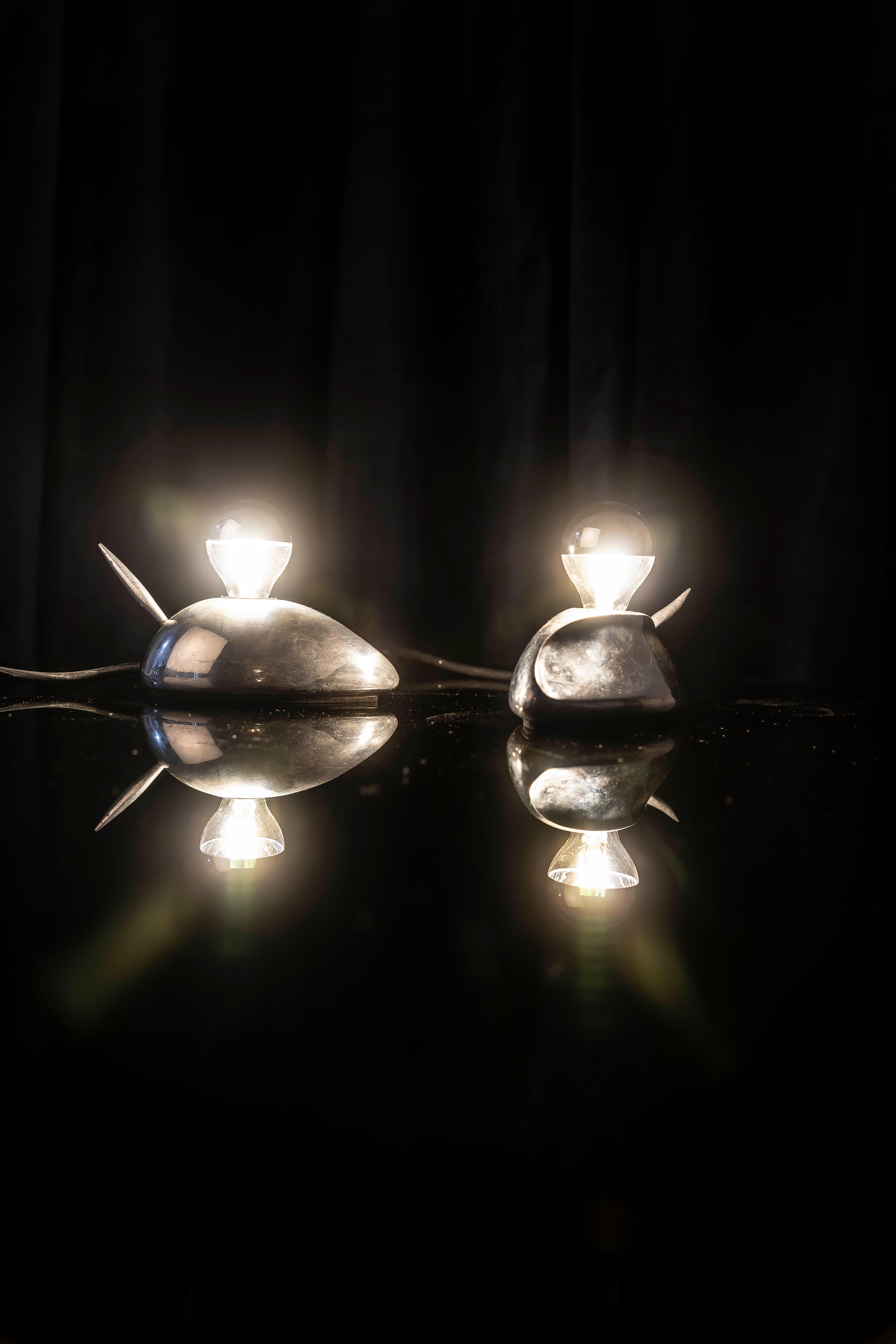 Playful and iconic pair of “Pixie” table lamps designed by Jorge Pensi, Spain, 1990s.

These lamps are an outstanding example of Pensi’s ability to merge organic inspiration with functional design. The streamlined aluminum body, with its curved and