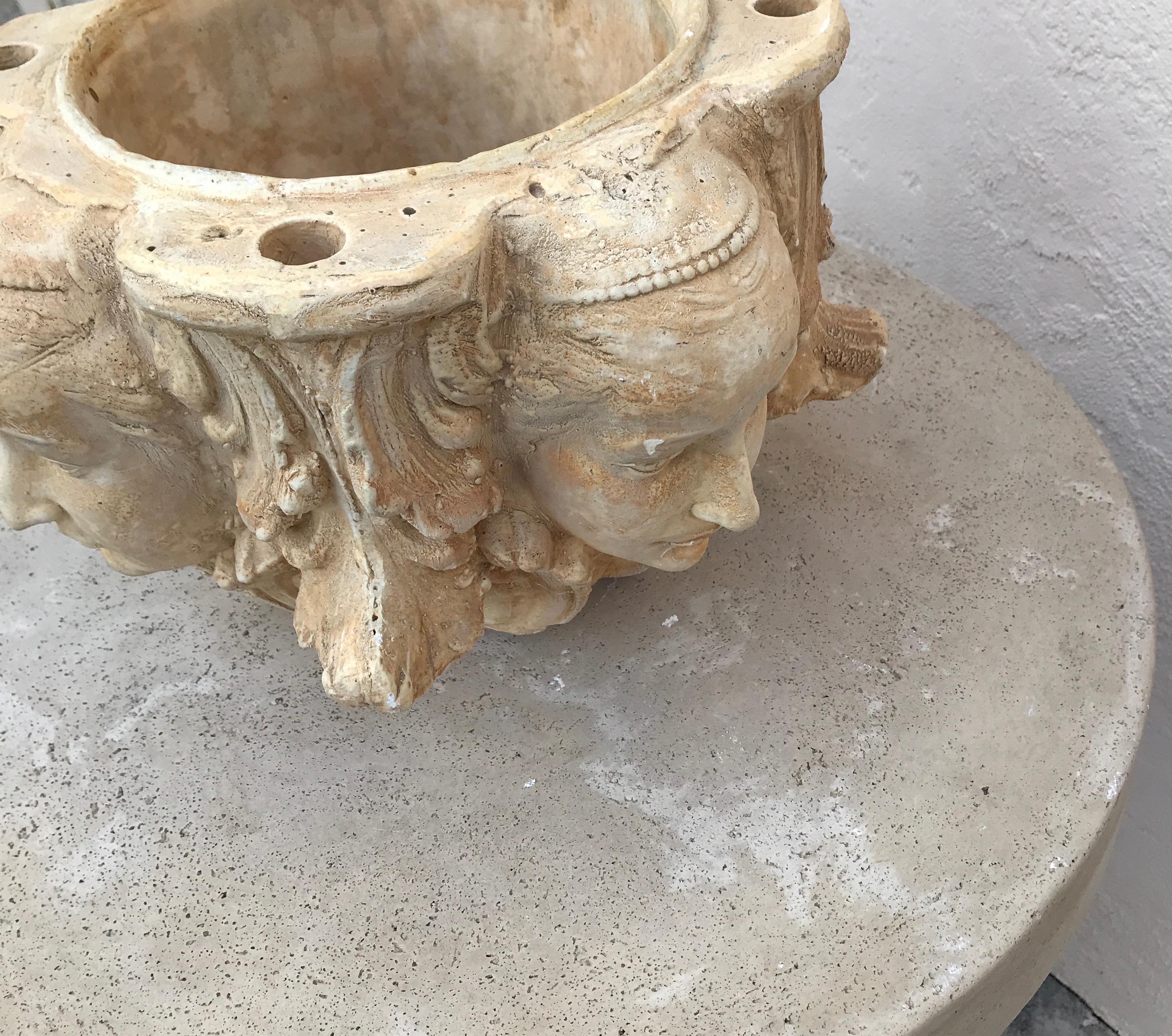 Neoclassical pair of cast stone planters with faces on each side and four holes for candles on top edge.
