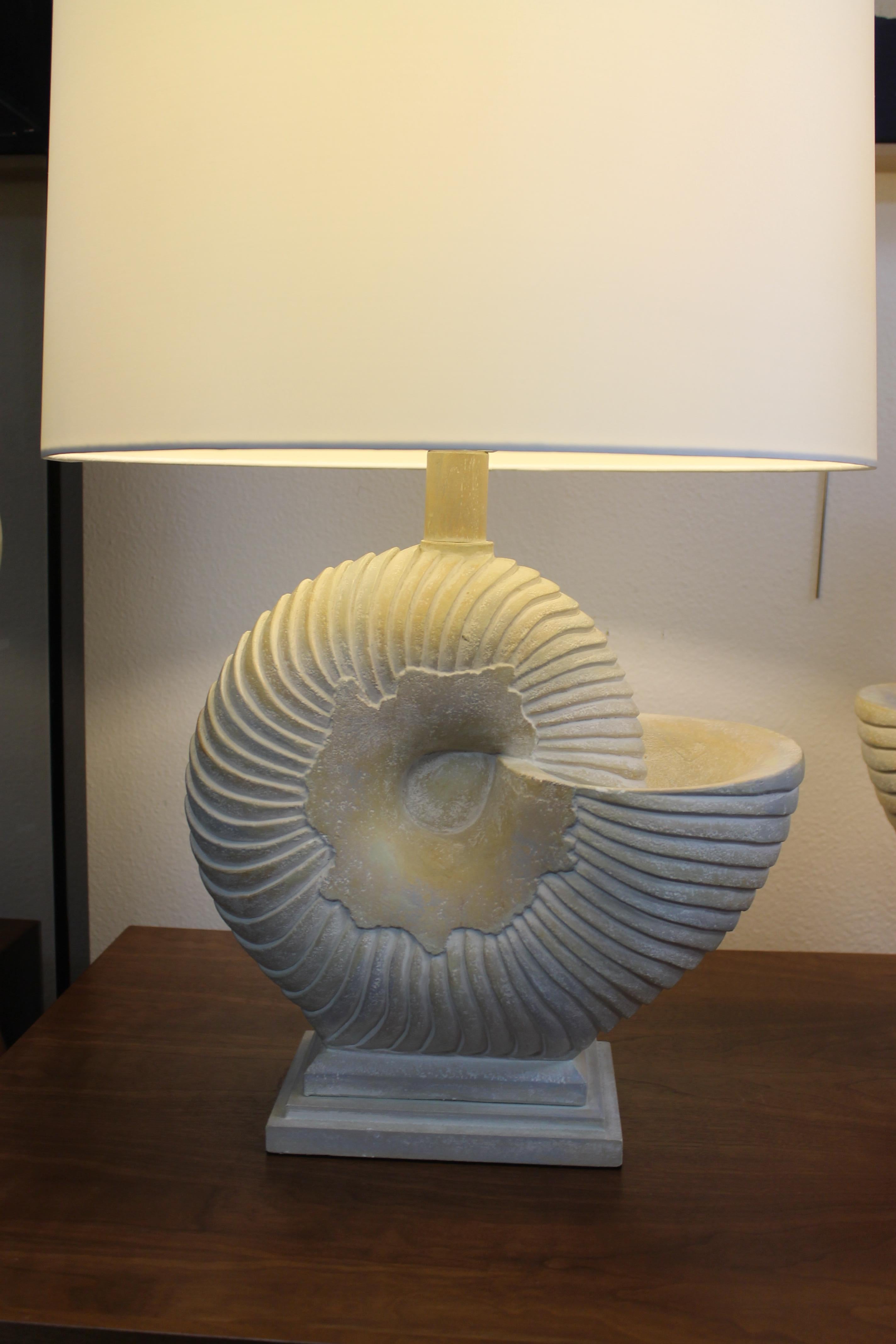 Pair of plaster composite nautilus lamps. They are signed but, we cannot make out the company name. They measure 14” wide, 8.75” deep and 16” high from the base to the bottom of socket. Base is 8” wide, 5.5” deep. Lamps have been professionally