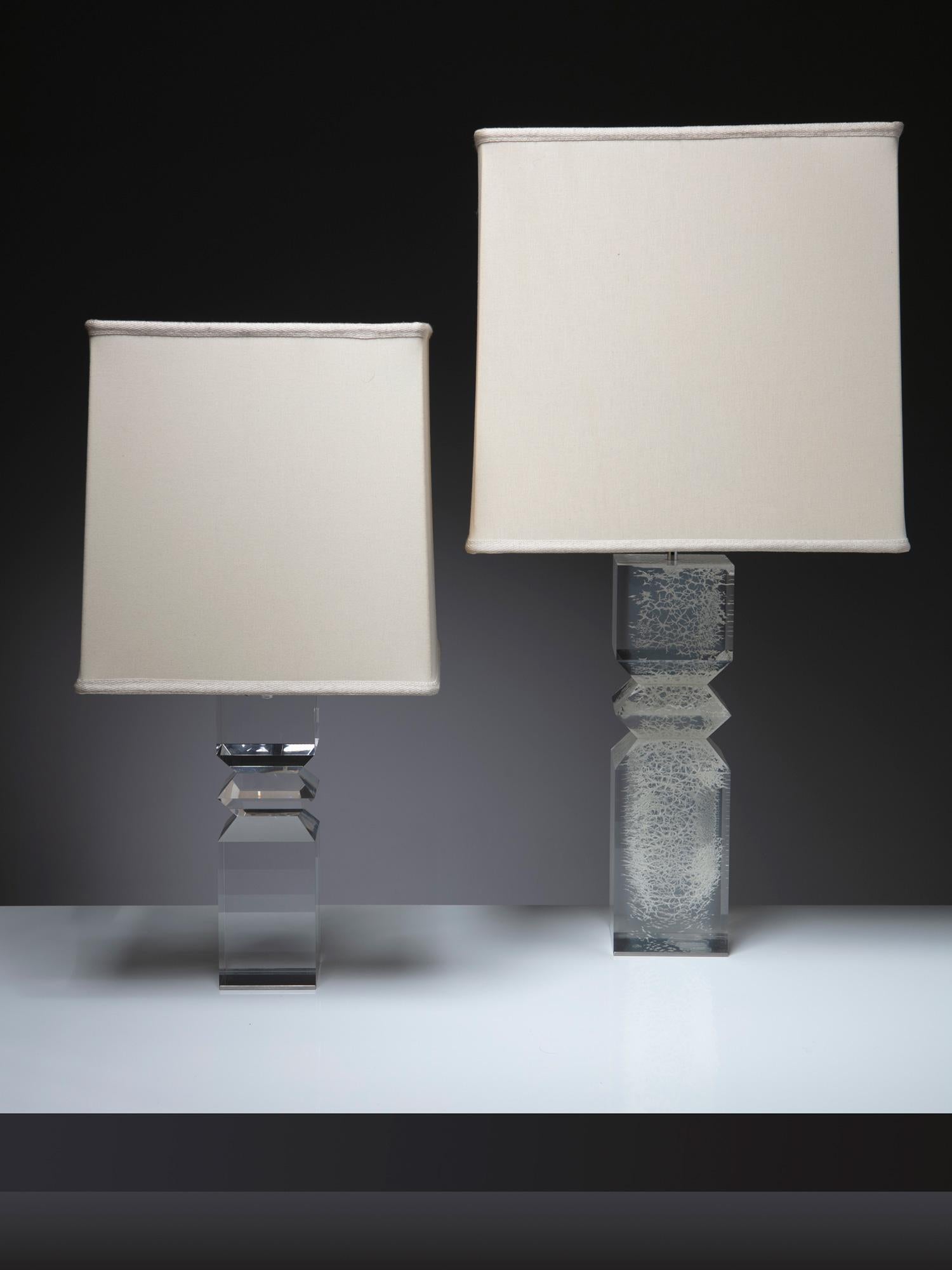 Pair of Plexiglass table lamps by Alessio Tasca for Fusina.
Part of Tasca's sculptural sperimetation for domestic objects, these lamps feature a solid plexiglass body with geometric cuts, aluminum base and a squared shade.
The taller piece shows a