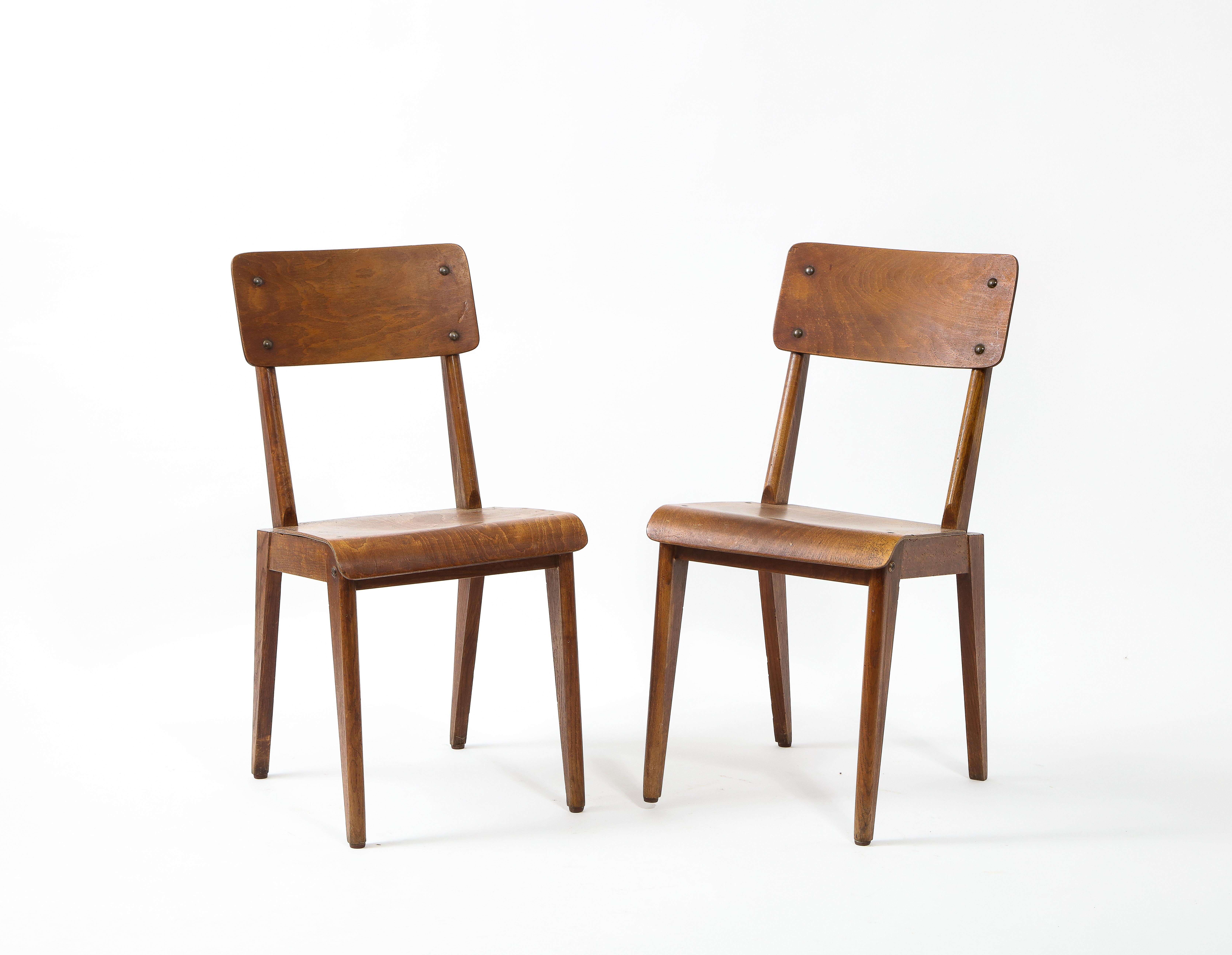 A pair of plywood chairs from the post-war reconstruction period with canted back legs.