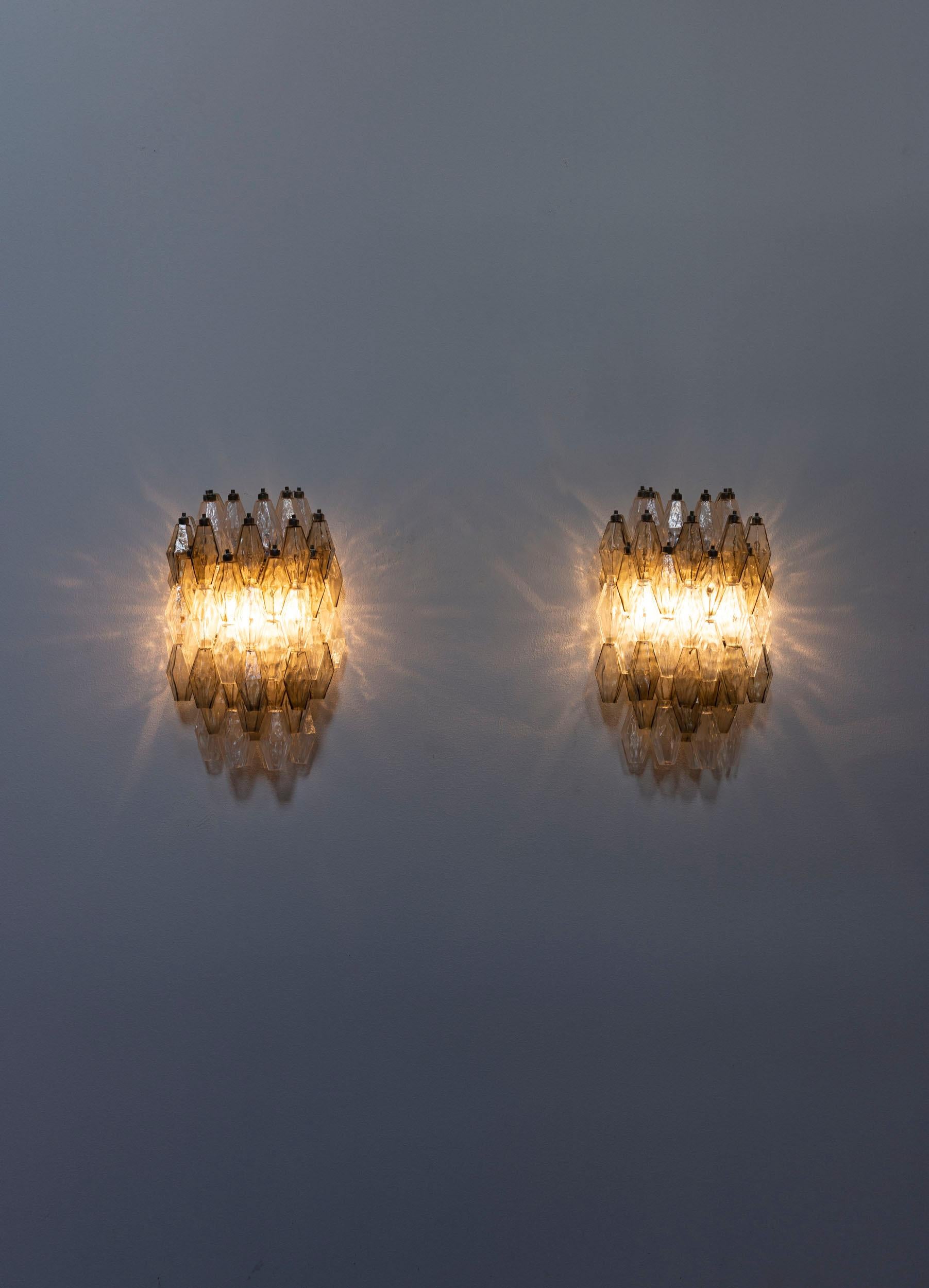 A rare pair of poliedri wall lamps attributed to Carlo Scarpa for Venini,  featuring hand-blown Murano glass with a mix of transparent and soft grey tones. The metal structure supports a high number of polyhedrons, enhancing their distinctive