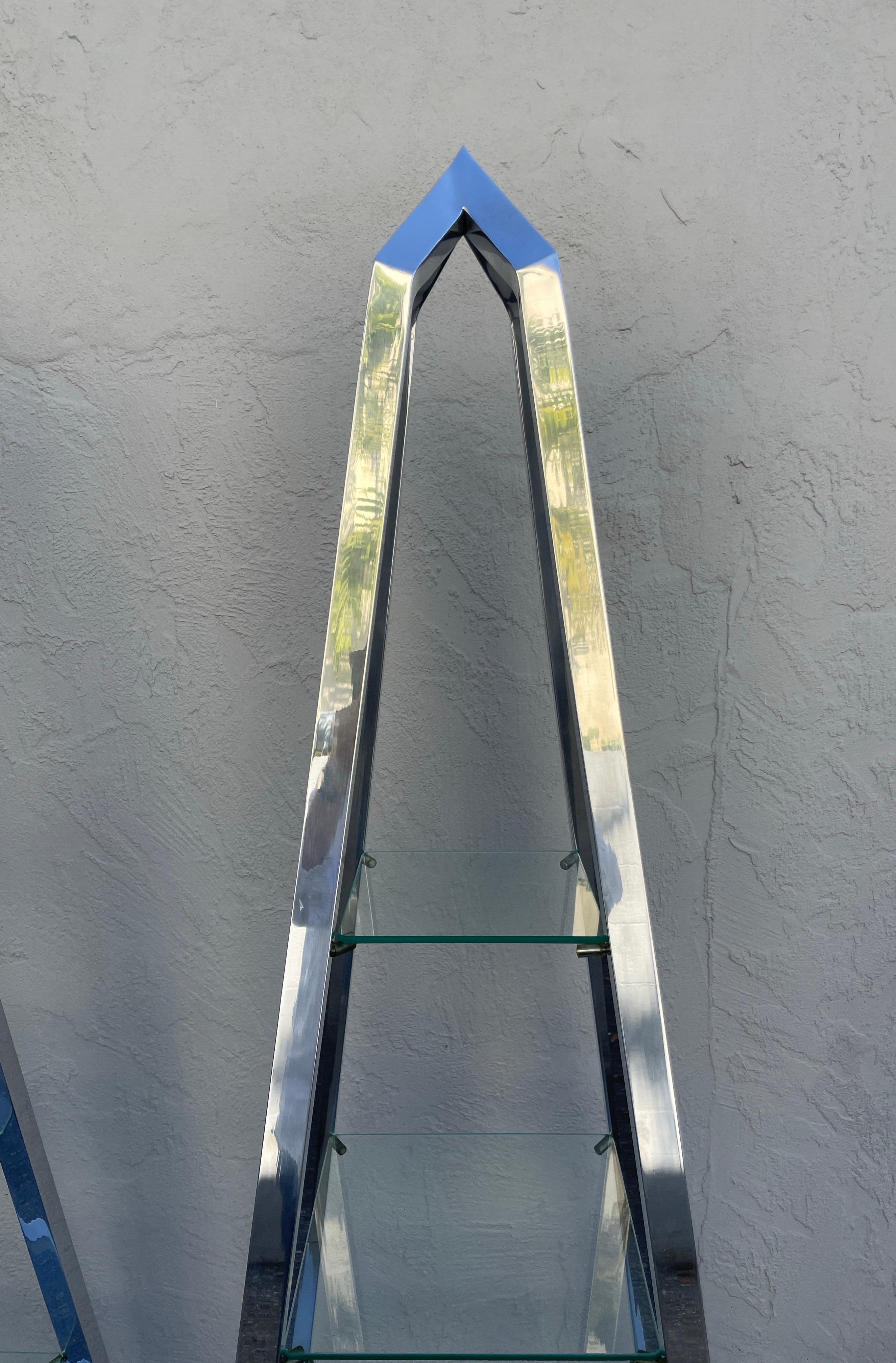 Splendida coppia di Obelisco in alluminio lucidato a specchio con cinque ripiani. Il ripiano inferiore è a specchio e gli altri sono in vetro trasparente.