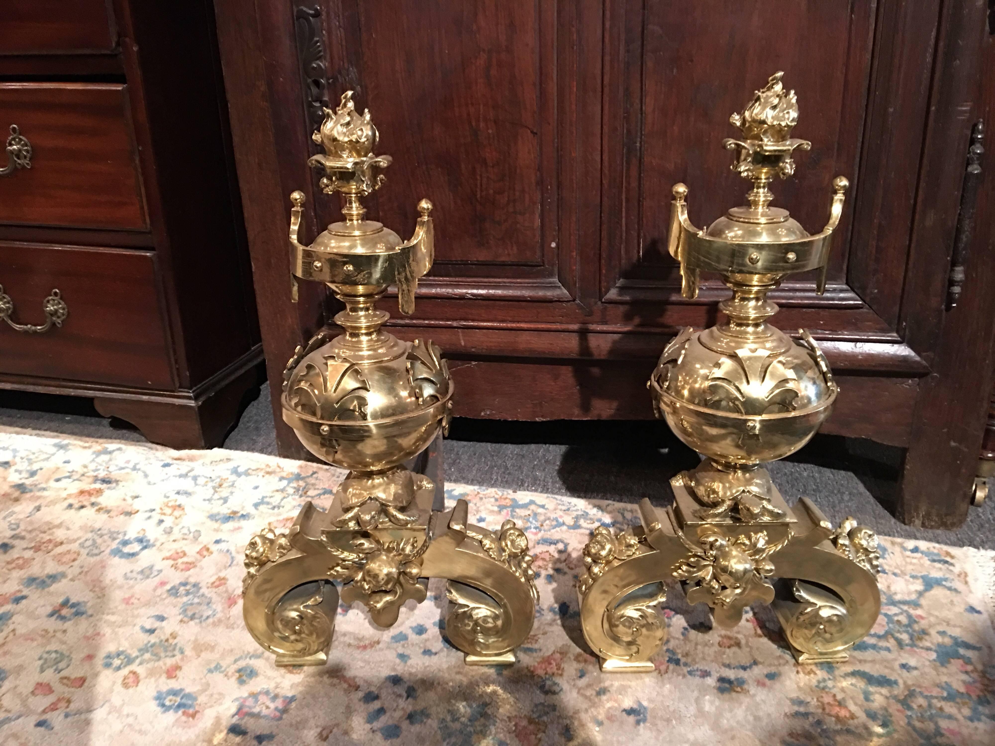 Pair of polished brass chenets or andirons with flame finials, 19th century.