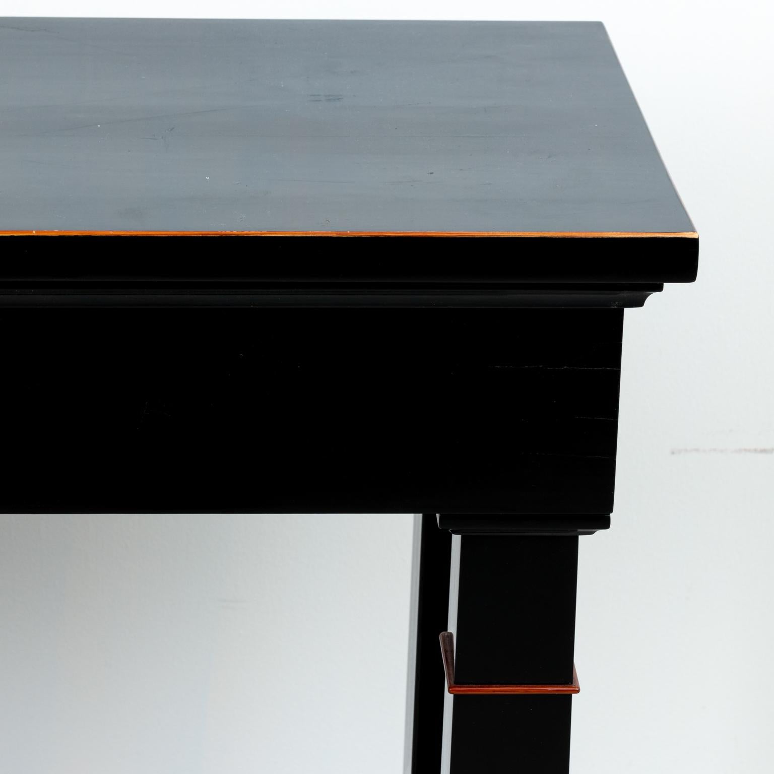 Pair of ebony wood console tables with bottom shelf in a polished finish. Please note of wear consistent with age including minor finish loss.