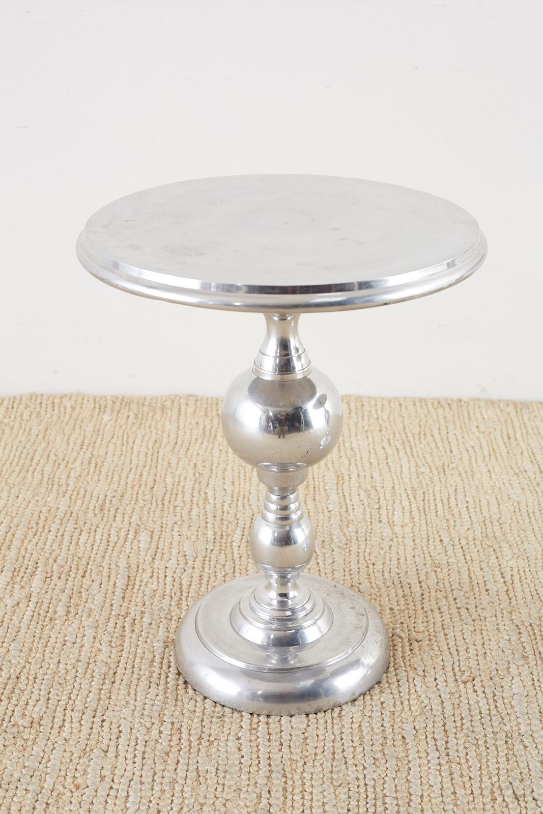 Sleek pair of round pedestal drink tables or side tables made of metal, probably aluminum. Featuring a turned style column pedestal mounted on a round base. The top has an ogee decorative edge and the tables have a polished finish with a vintage