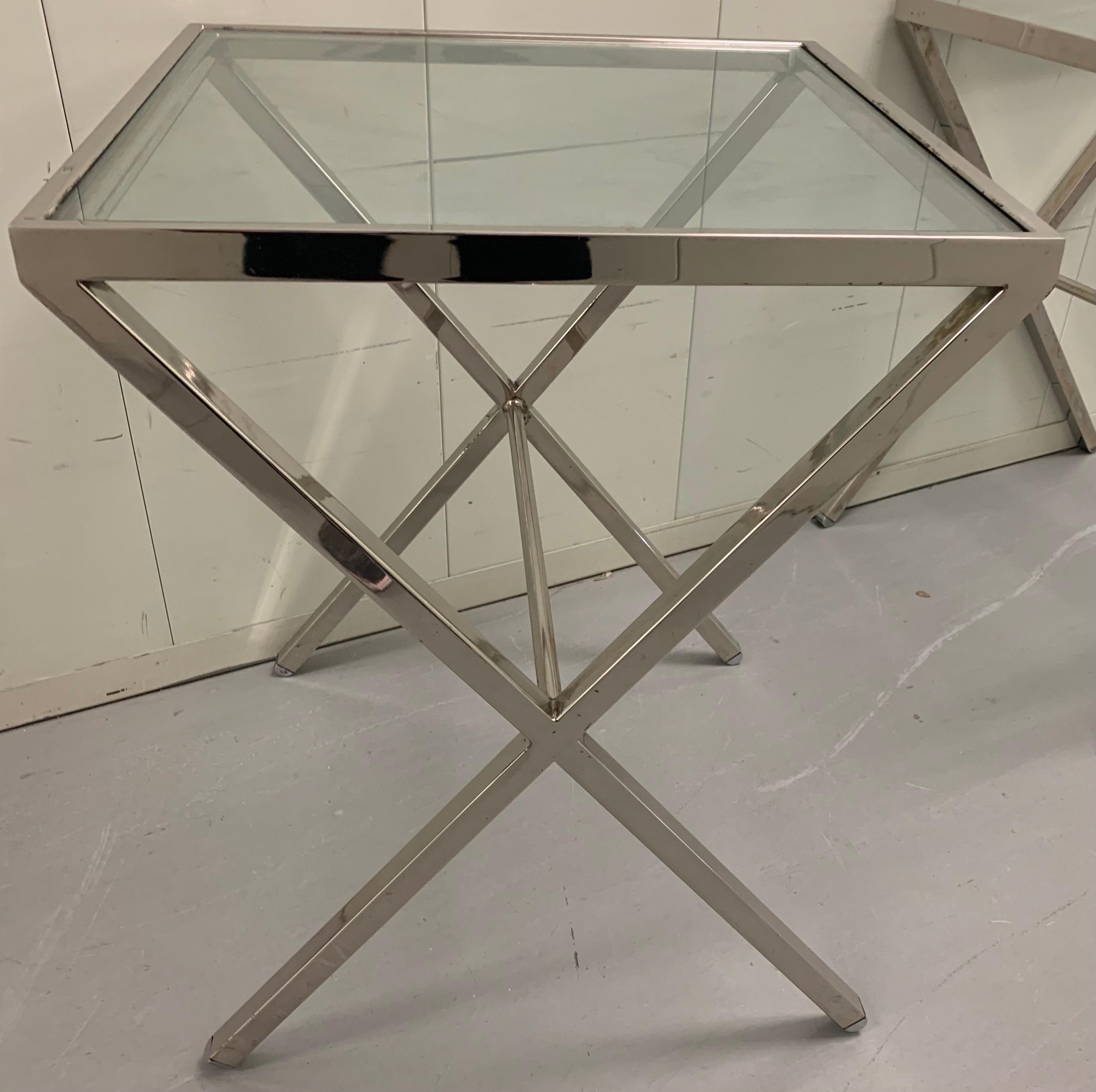 Pair of polished steel X- frame side tables. Tables are newly polished to a high shine. As found tinted grey glass tops with minimal overall wear. No makers mark or signature.