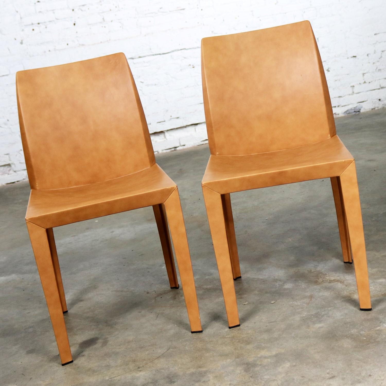 Handsome pair of Lola cognac colored leather dining side chairs. Designed by Pierluigi Cerri for Poltrona Frau in 1997. This vintage pair are in wonderful condition. There are small nicks and scratches as would come with age and use but nothing