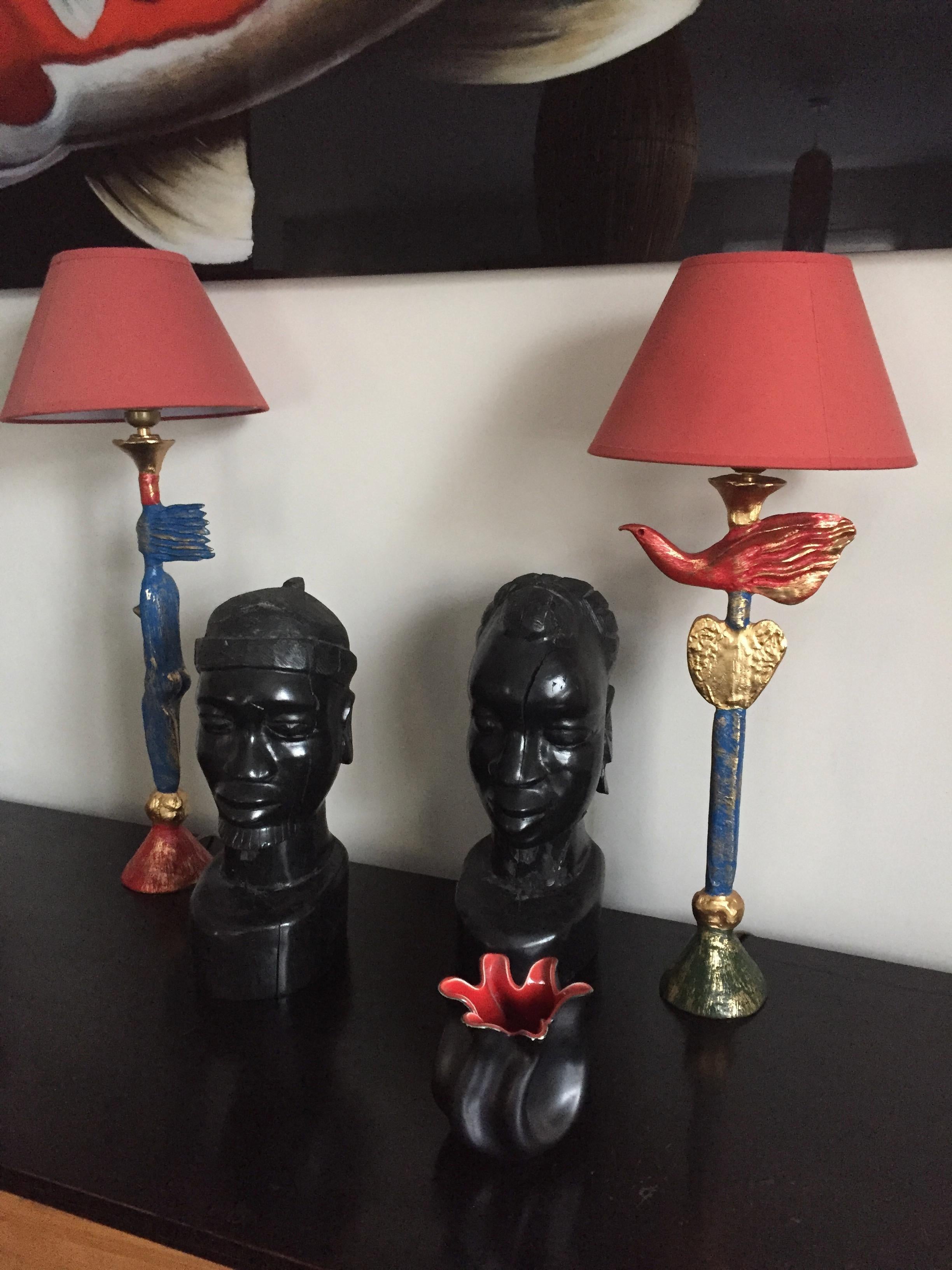 Pair of polychrome bronze lamps decorated with a bird and a woman in the style of Cocteau. They are surmounted by a red lampshade. Signed 