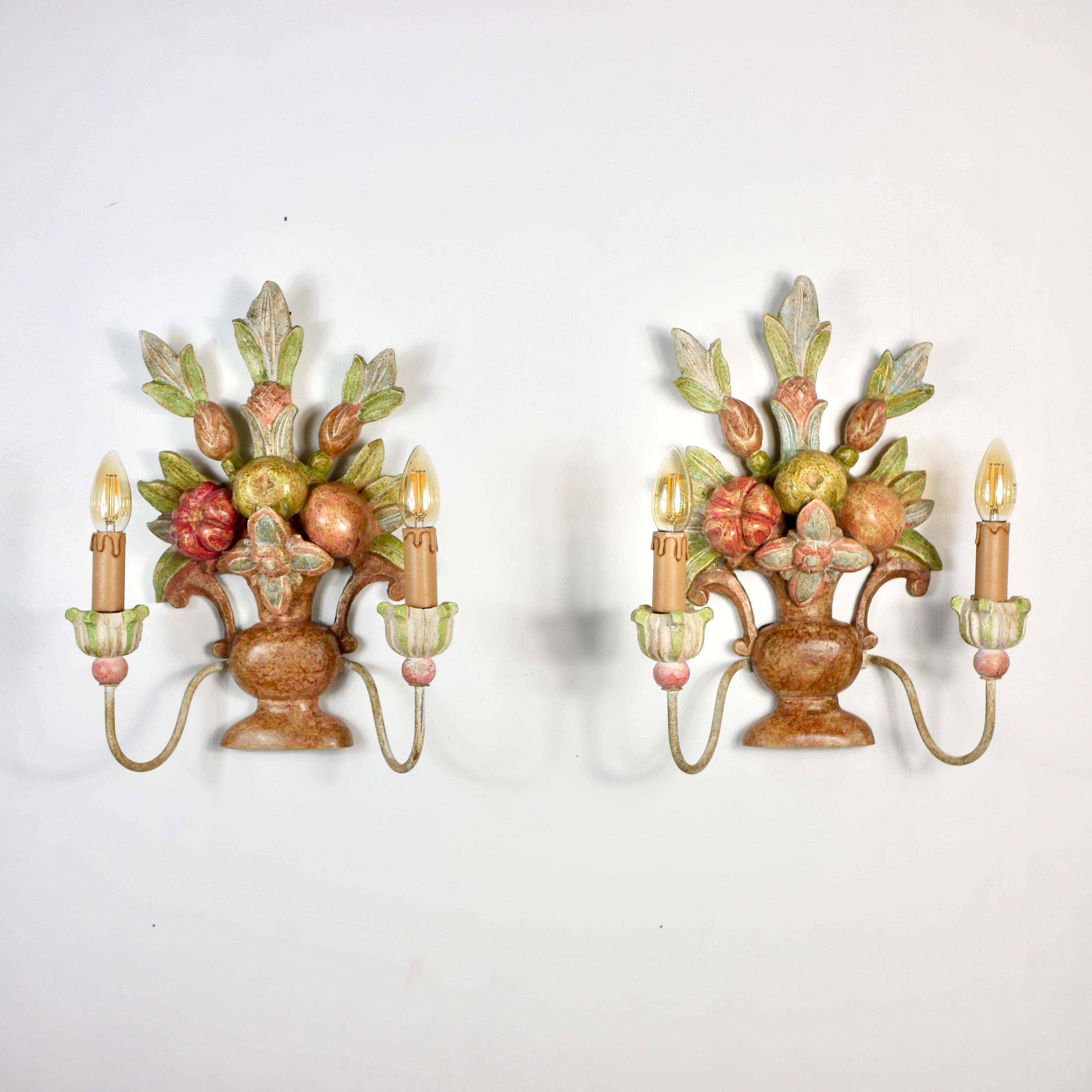 Precioso par de apliques de madera tallada a mano, fabricados en Italia a principios del siglo XX, que representan ramos/cestas de flores, hojas y frutas, al estilo de la Maison Jansen.
Pintado a mano, cada candelabro tiene dos 