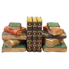 Coppia di reggilibri "Libri impilati" in legno intagliato policromo