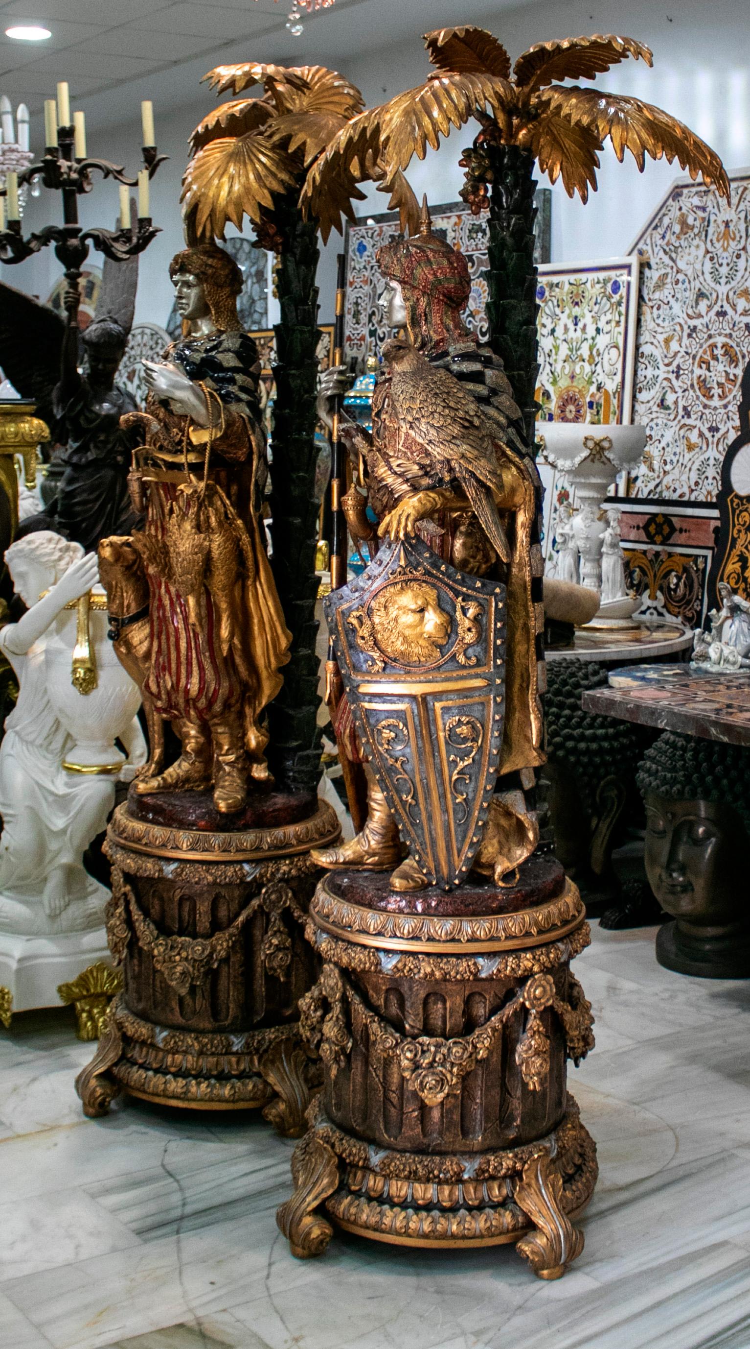 Pair of polychrome gilded bronze Arab hunters and palm tree sculptures on pedestals, representing a hunter and a falconer, accompanied by a dog and a falcon respectively.

Golden, silvered and colorful polished finish credit this pair of