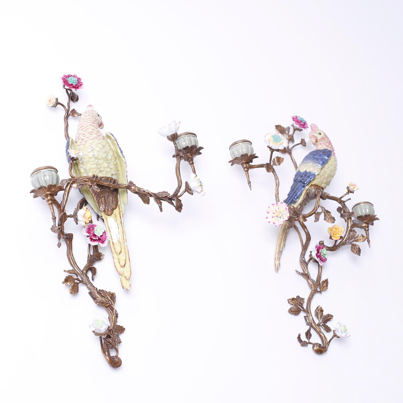 Pair of vintage wall sconces with colorful porcelain parrots, flowers, and candleholders supported by brass branches with leaves.