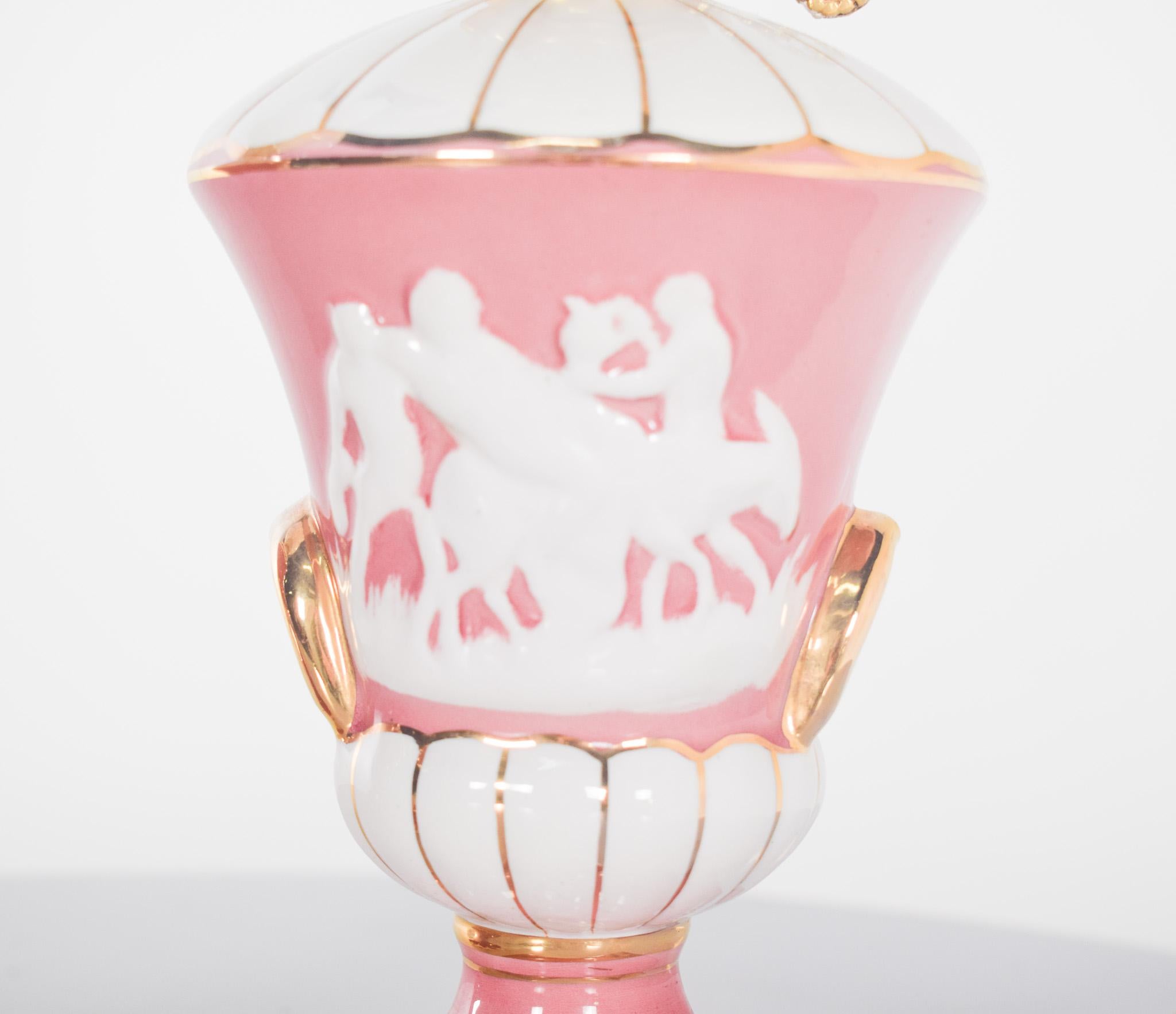 Pareja de lámparas de mesilla de noche de porcelana. Decorado en rosa, blanco y dorado. Están formados por una base de porcelana esmaltada rosa, ricamente decorada con camafeos en relieve blanco que representan escenas bucólicas. El contraste entre
