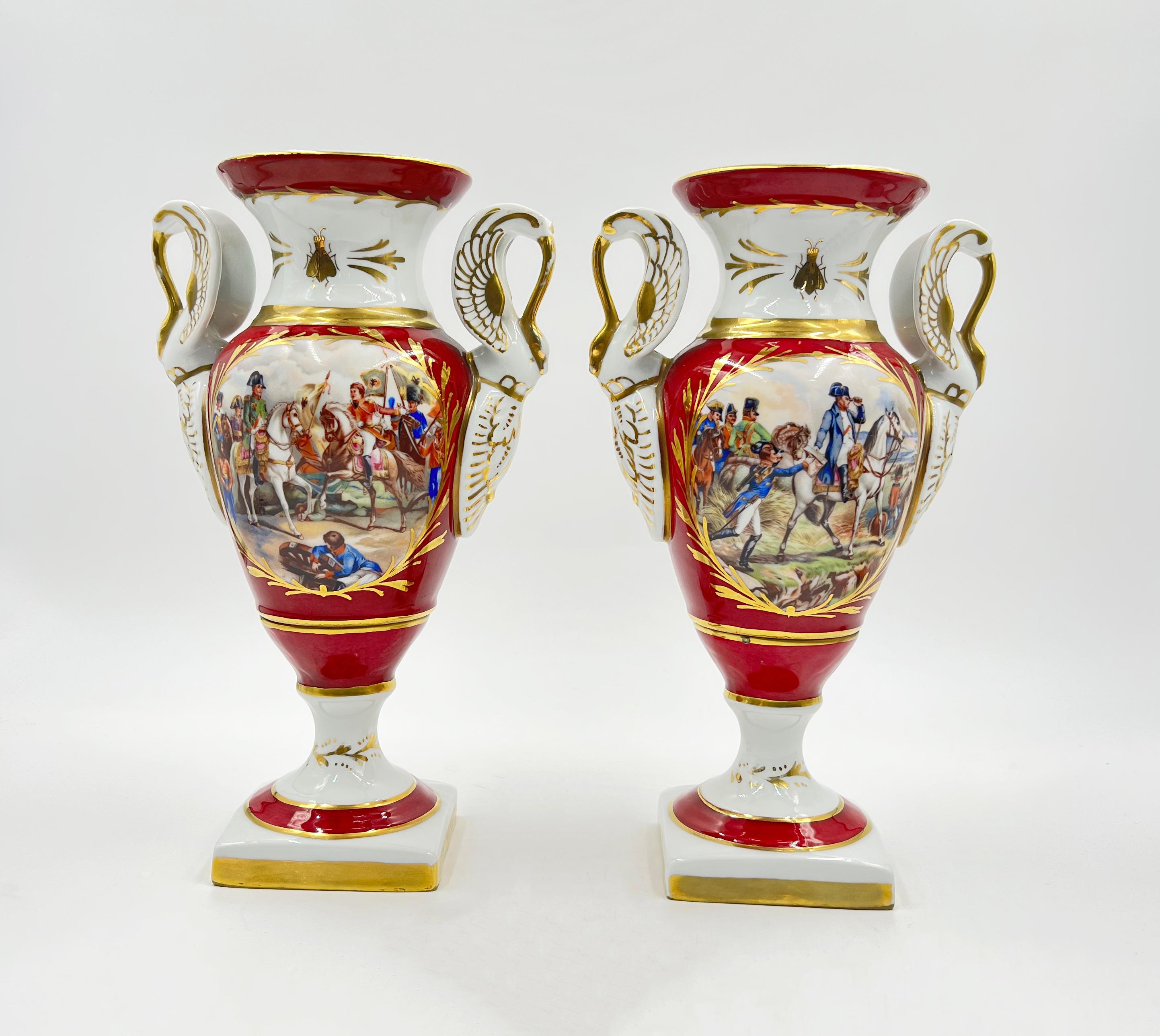 Pair of antique French porcelain vases, the front of the vases hand painted with battle scenes, while the reverse decorated with golden eagles, the sides decorated with swan-shaped handles and raised on a square base.
   