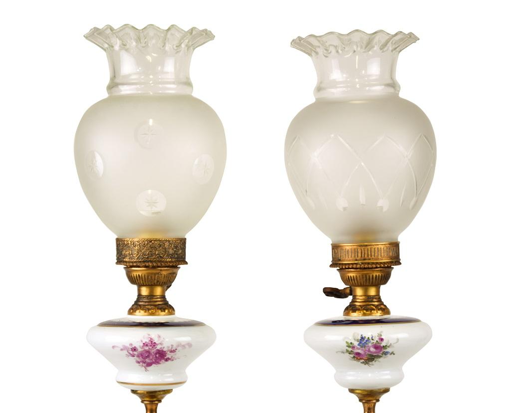 Pair of porcelain lamps is an original couple of decorative porcelain lamps realized by French manufacture during the 20th century. 

This pair of table oil lamps in porcelain is painted in burgundy and blue and has beautiful gold highlights. The