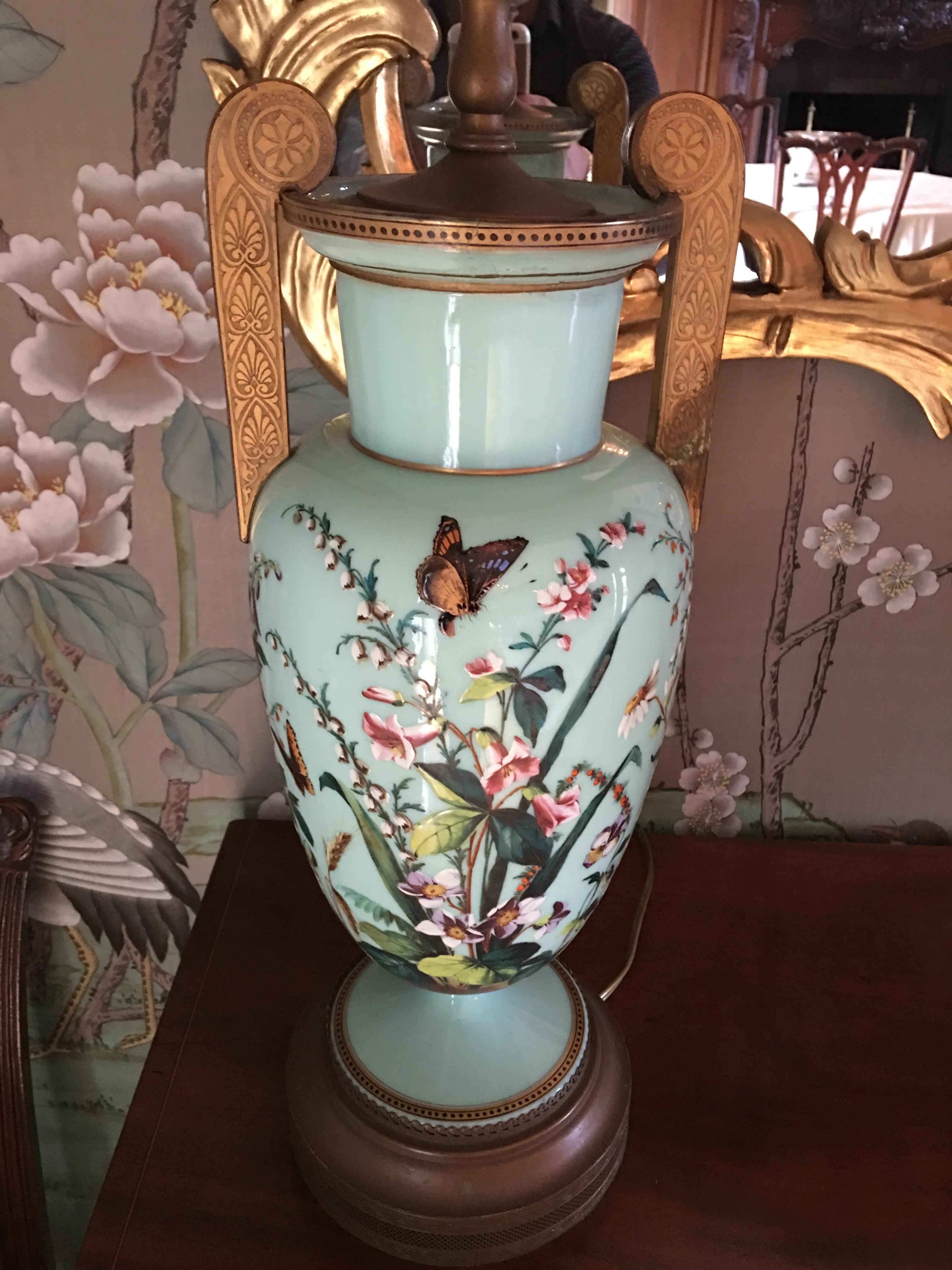 20th century pair of porcelain lamps in an aqua color background with flowers and butterflies design on metal gold vases.