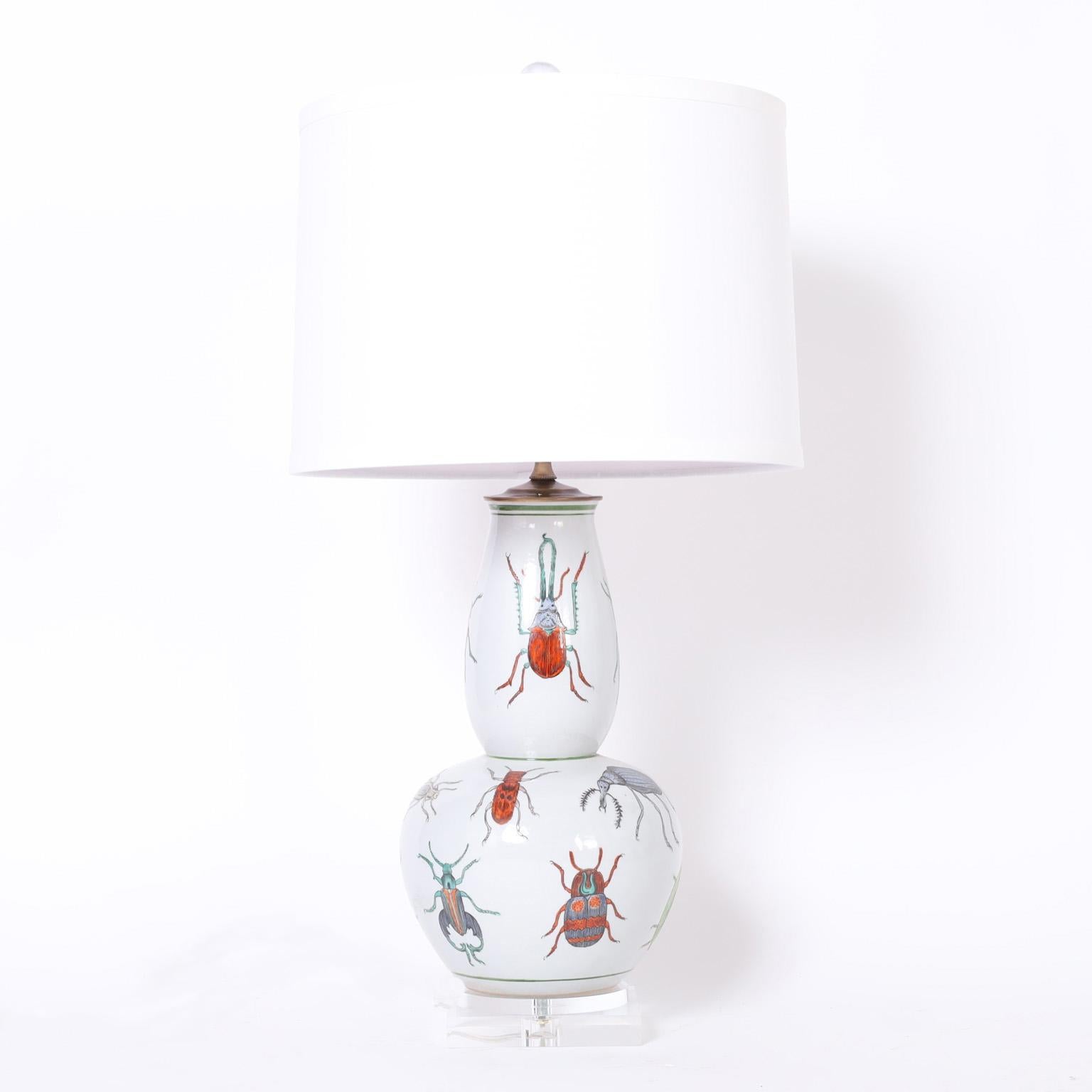 Striking pair of Chinese table lamps crafted in porcelain in a classic form, hand decorated with insects and presented on lucite bases.