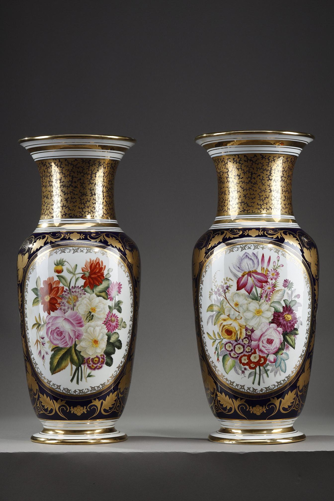 Pair of Bayeux porcelain vases of baluster shape with flared neck. The body is decorated with a polychrome bouquet of flowers inscribed in a white oval reserve on one side and a stylized fleur-de-lis on the other. Blue background covered with vine