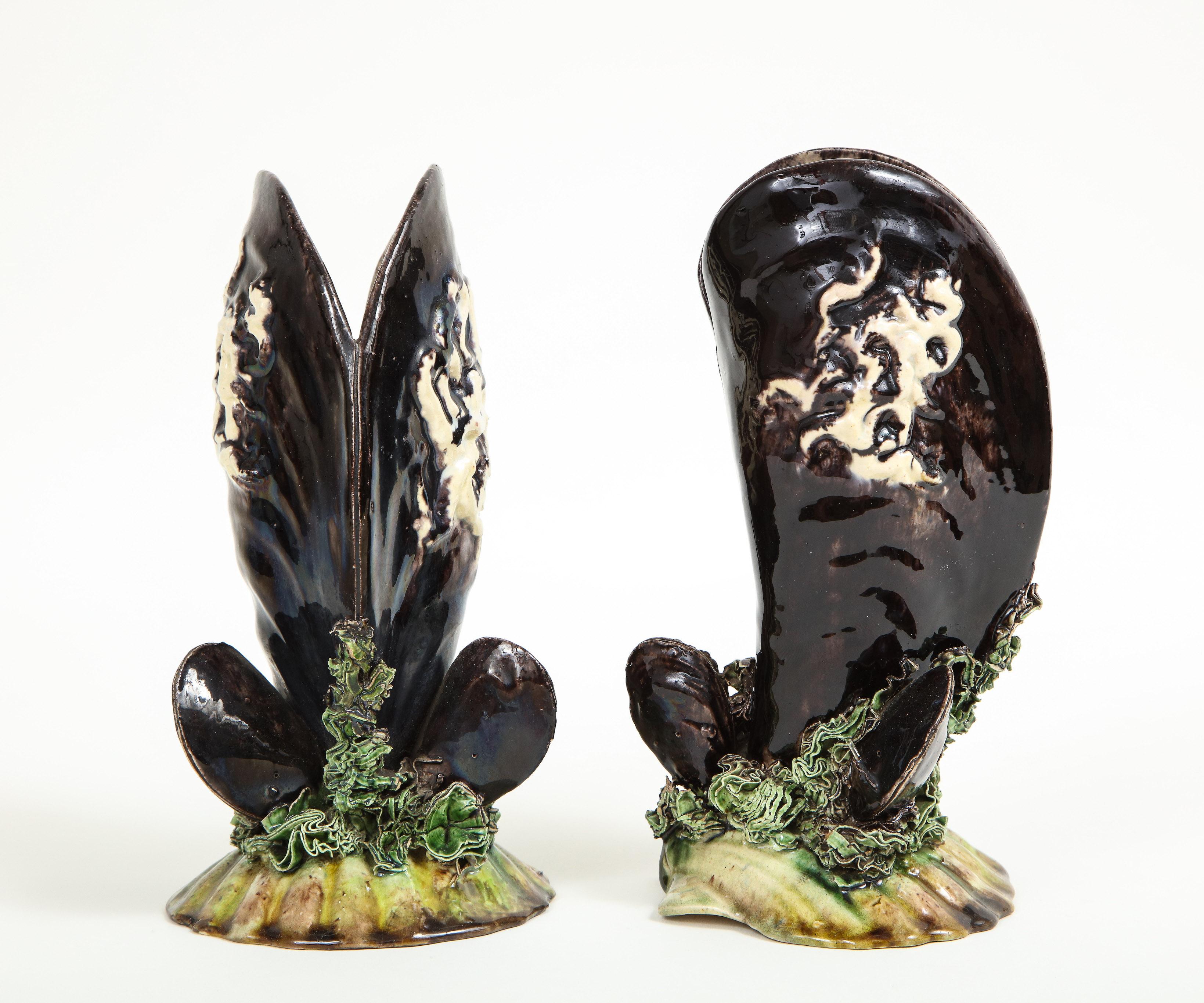 Unusually eccentric vases in the form of black mussel shells resting on a bed of seaweed and a scallop shell. Caldas da Rainhas factory mark on underside.