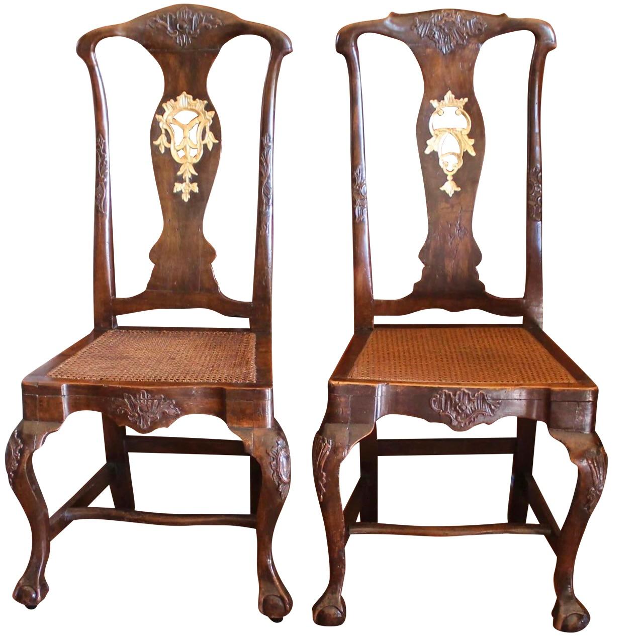 A near pair of very elegant carved walnut Portuguese chairs with parcel gilding, almost certainly from a larger set of dining chairs. Within the English inspired format of  ball and claw footed chairs, the carved Rococo elements have greater flare