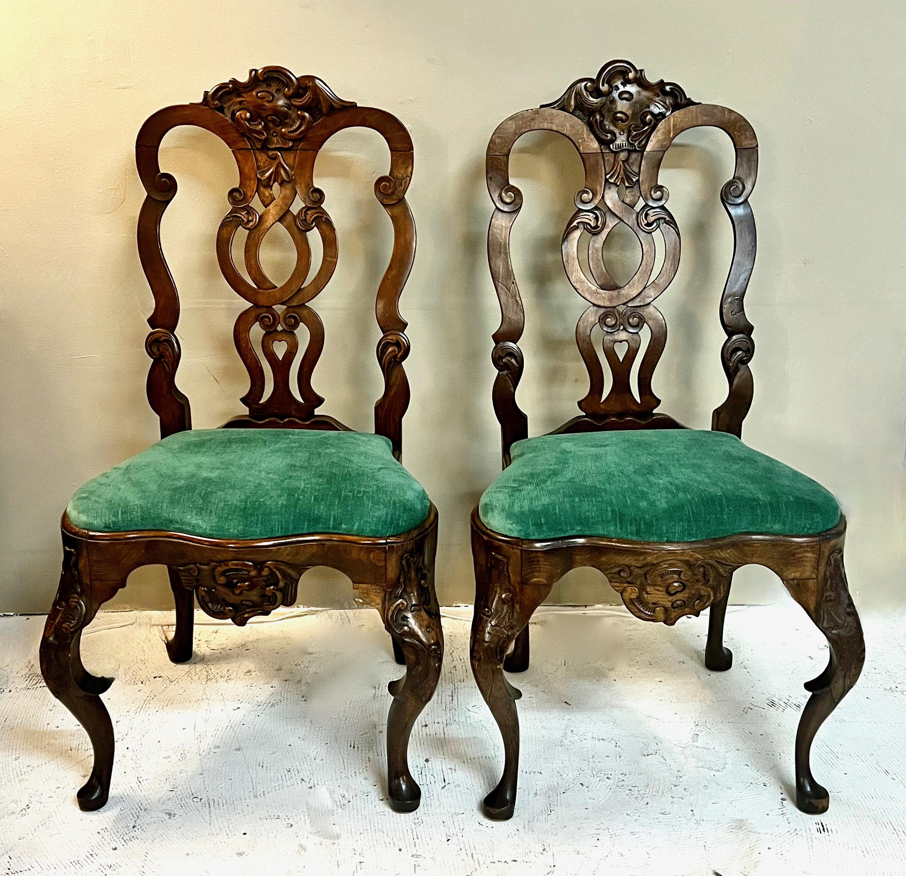 This is a great pair of carved Portuguese Oak Rococo side chairs. These chairs are beautifully carved with exaggerated cabriole legs detailed with carved knees, stirrups and pad feet. The center splat is whimsical with its scrolling carved openwork.